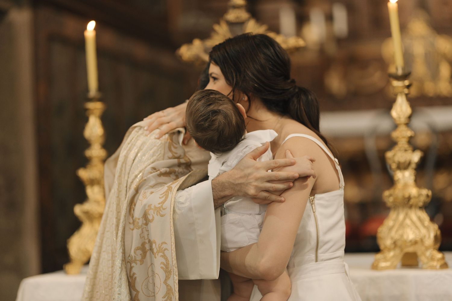 Couple sharing an intimate embrace in an ornate church setting with golden candelabras in the background.