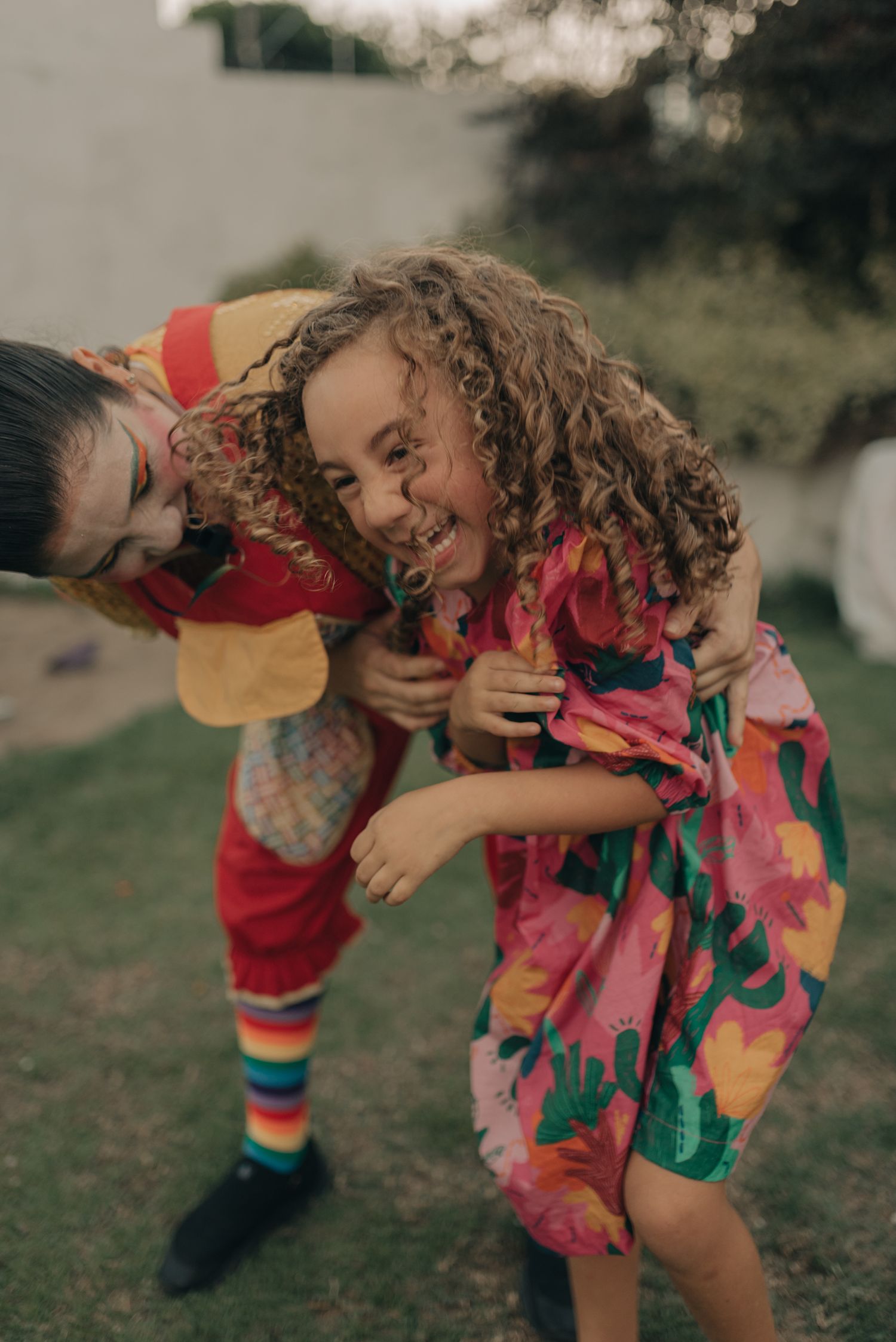 Two children laughing and playing together outdoors in vibrant colorful outfits.