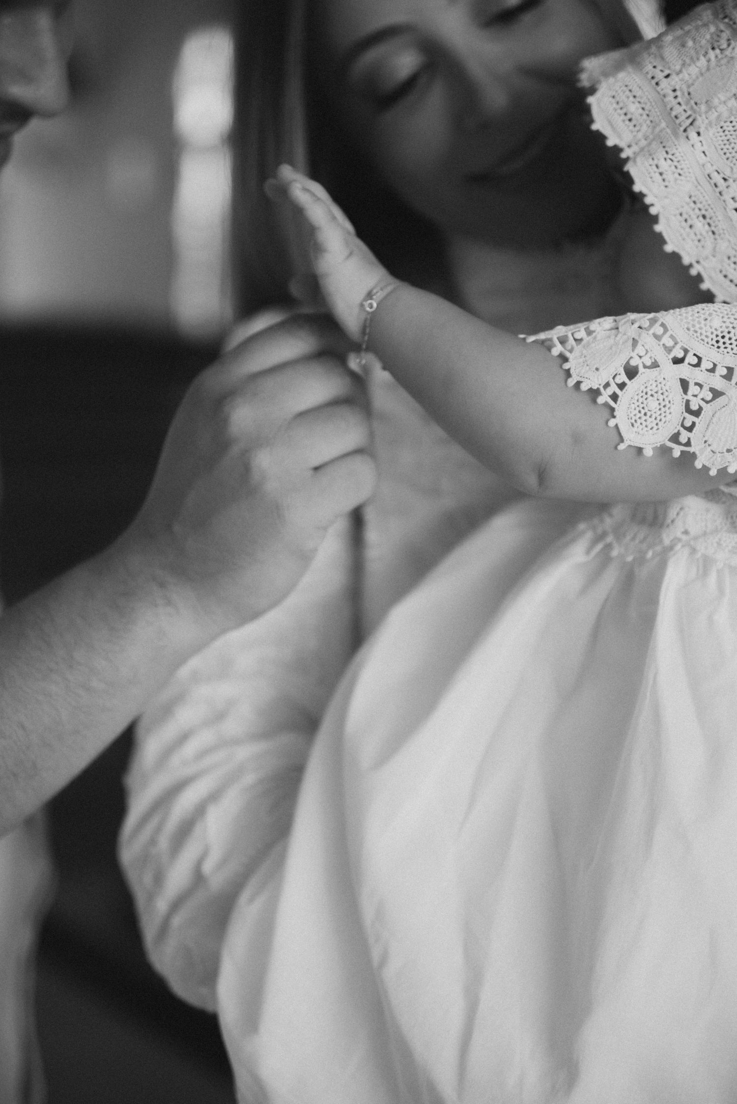 Close-up details of a delicate white lace christening gown with intricate embroidery patterns shown in black and white.