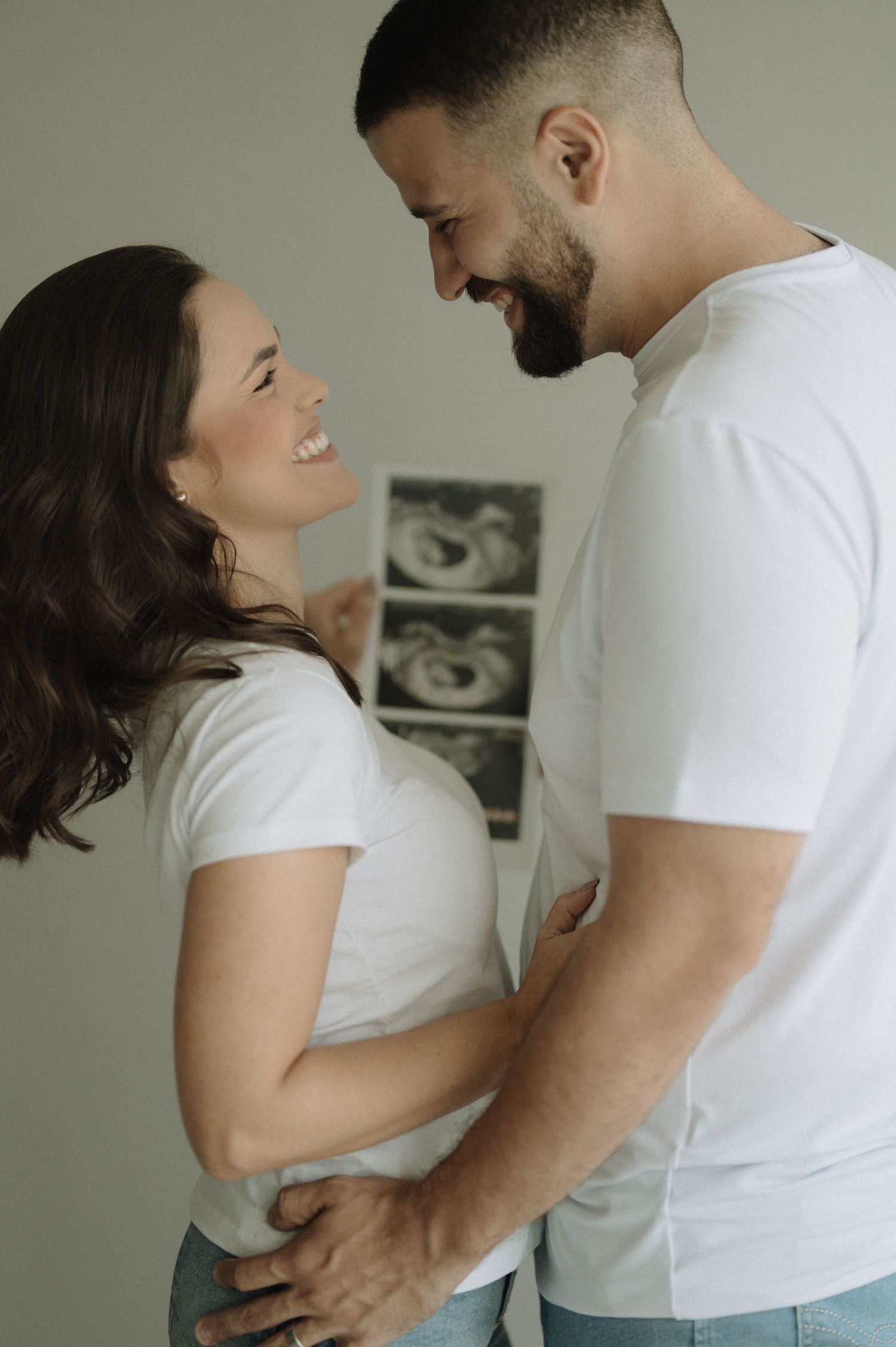 A couple in white t-shirts share intimate moments in a series of candid photos showing their affection and laughter.