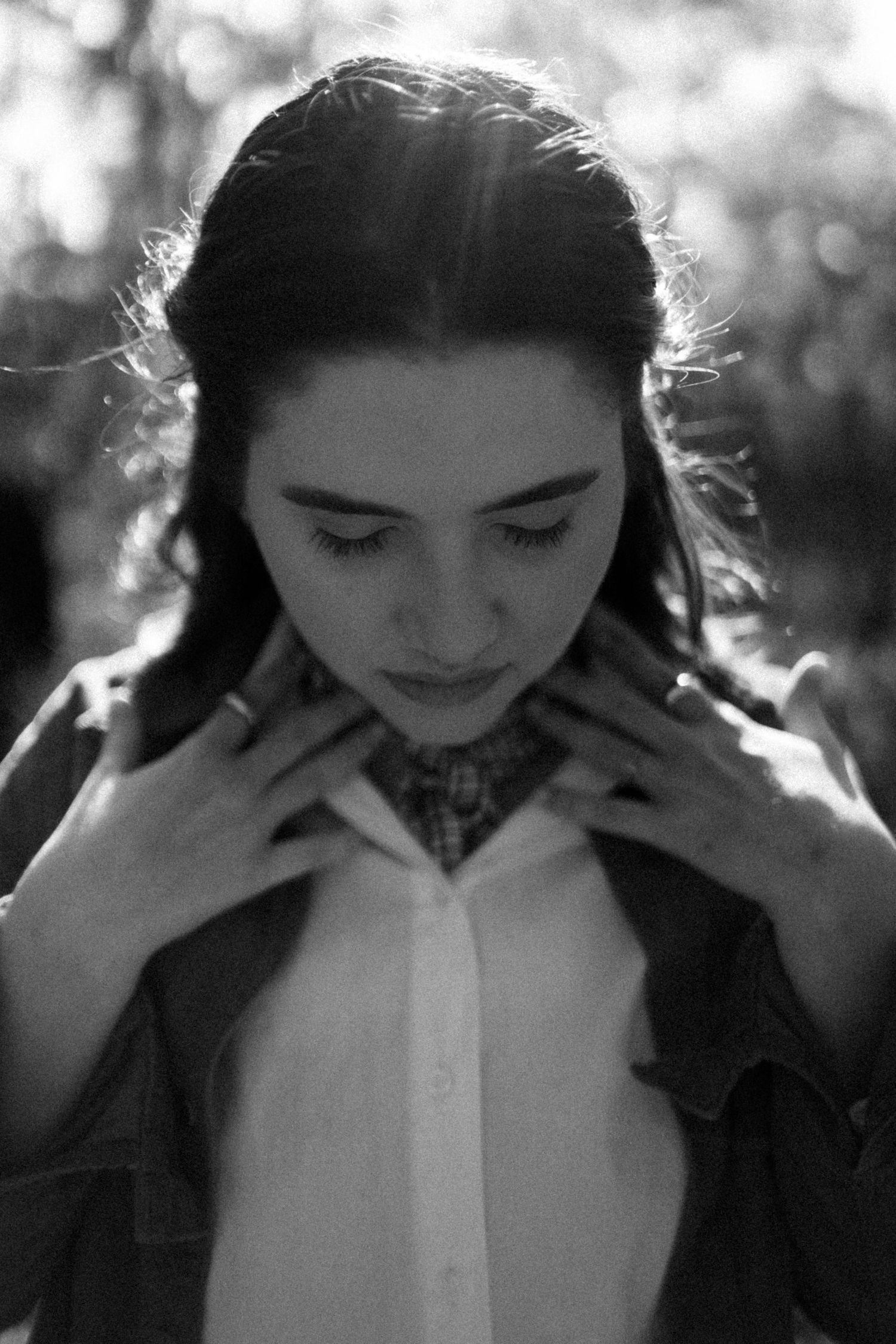 A series of black and white photographs showing a person in a white collared shirt looking down with changing expressions.