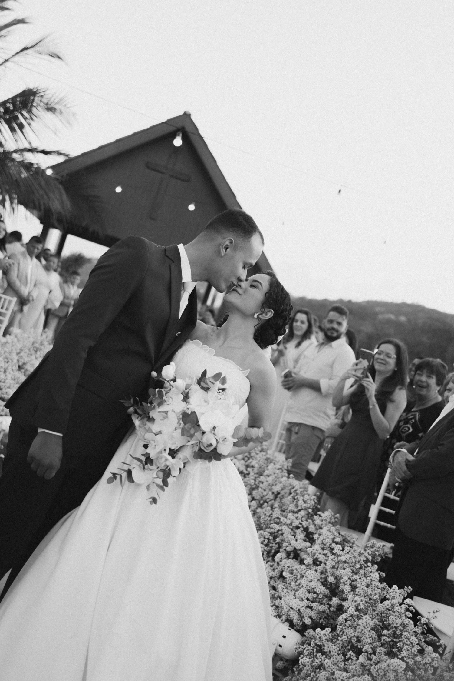 A romantic outdoor wedding moment under bistro lights and palm trees.