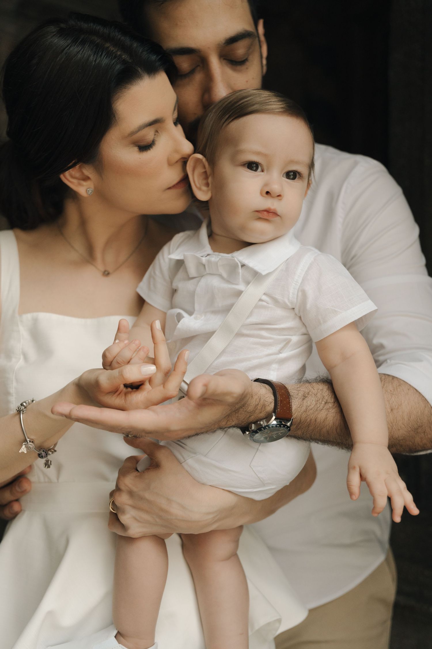 A tender moment captured in a series of black and white photos showing parent and baby in matching white outfits.