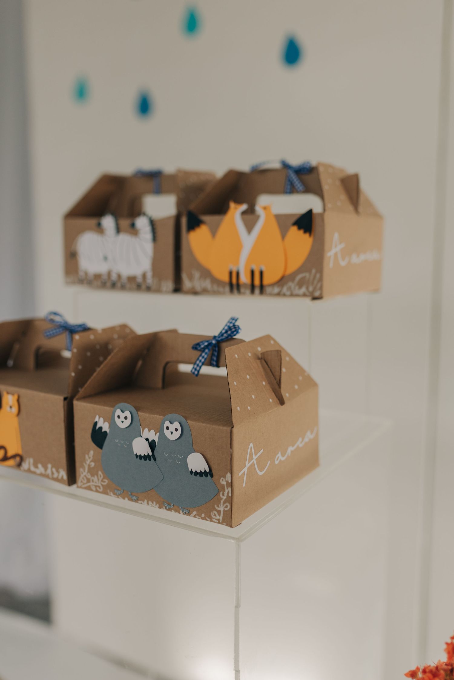 Decorative party favor boxes with cute animal designs and blue ribbons on display.