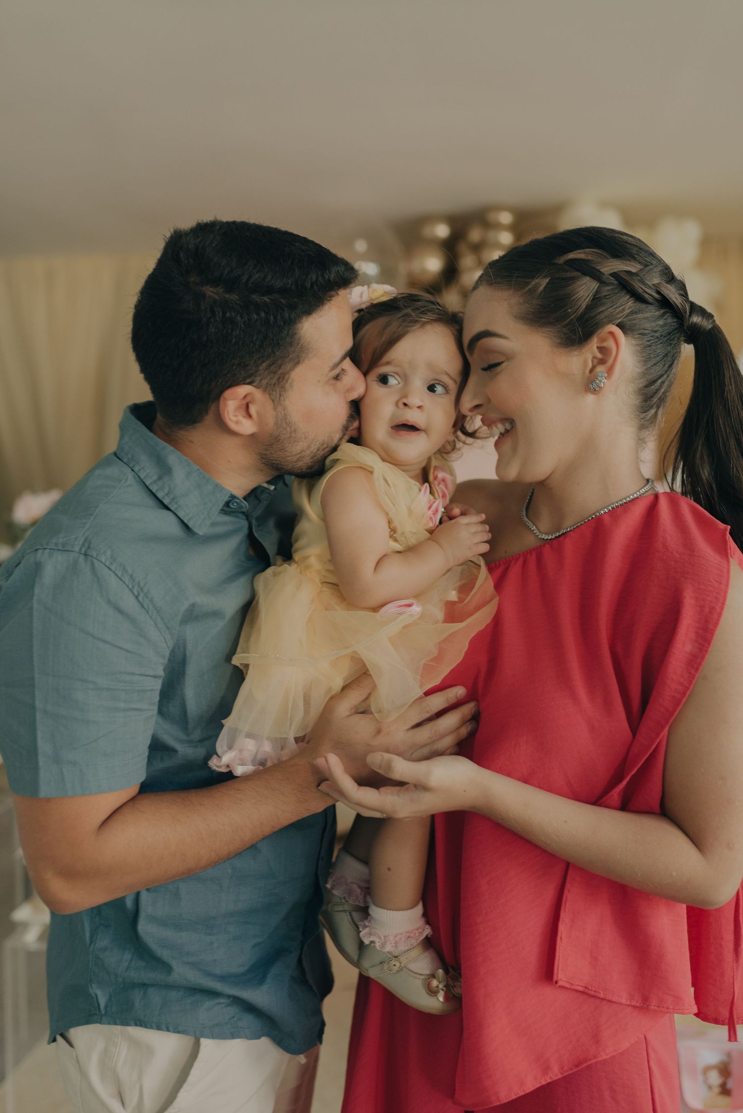 A joyful family moment during a celebration with pink and white balloon decor.