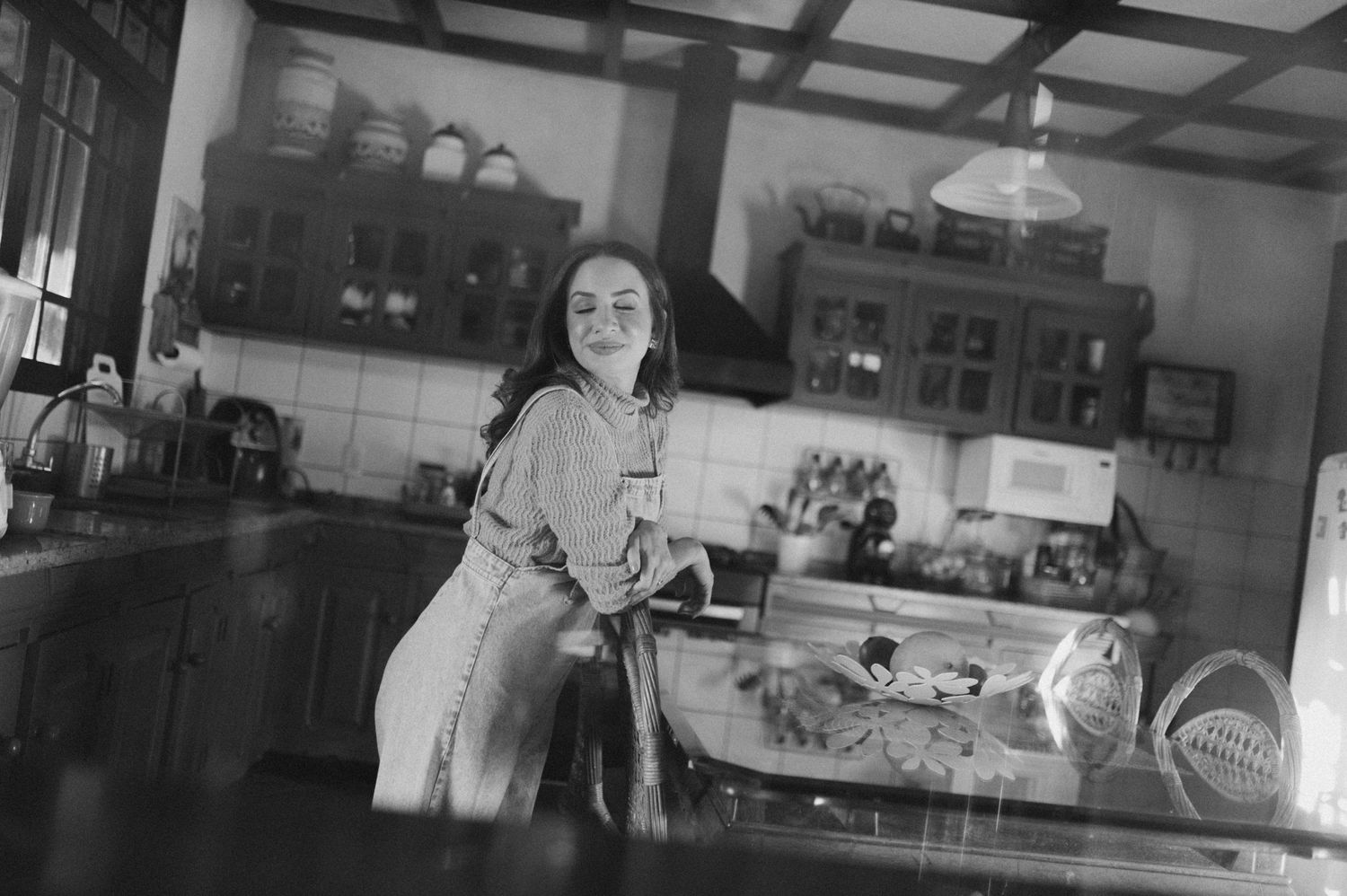 Vintage style black and white photo of someone in a rustic kitchen.