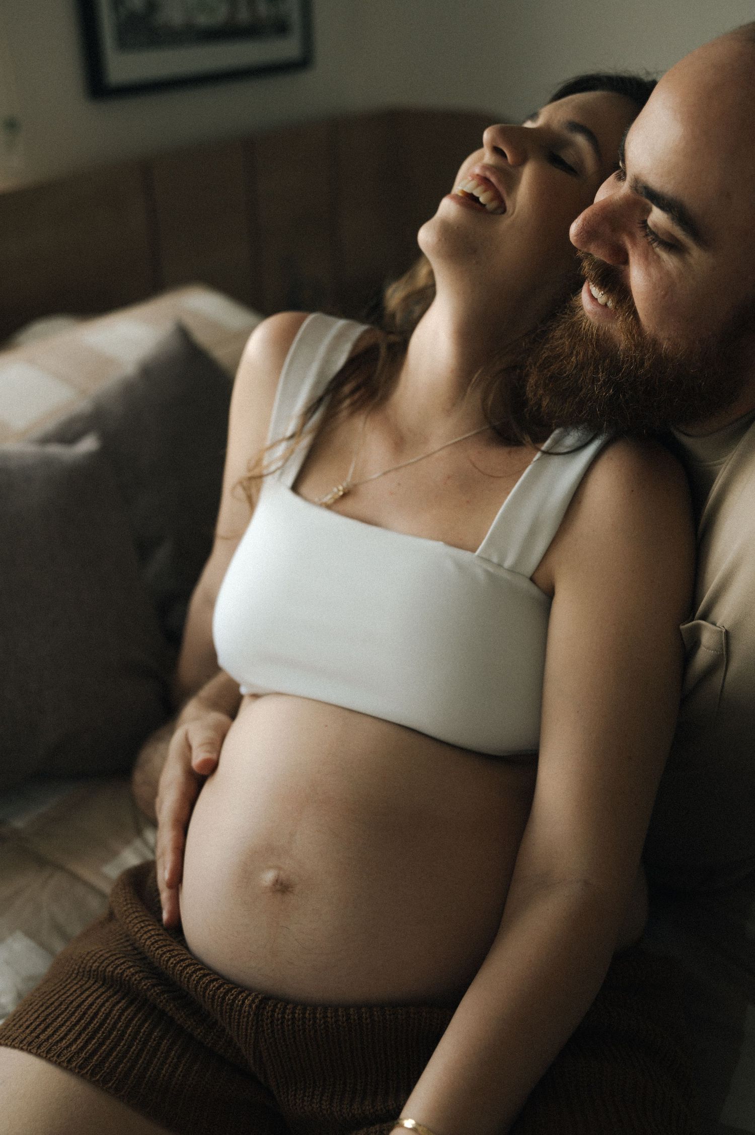 A series of intimate maternity photos showing a pregnant belly in soft, natural lighting against a dark background.