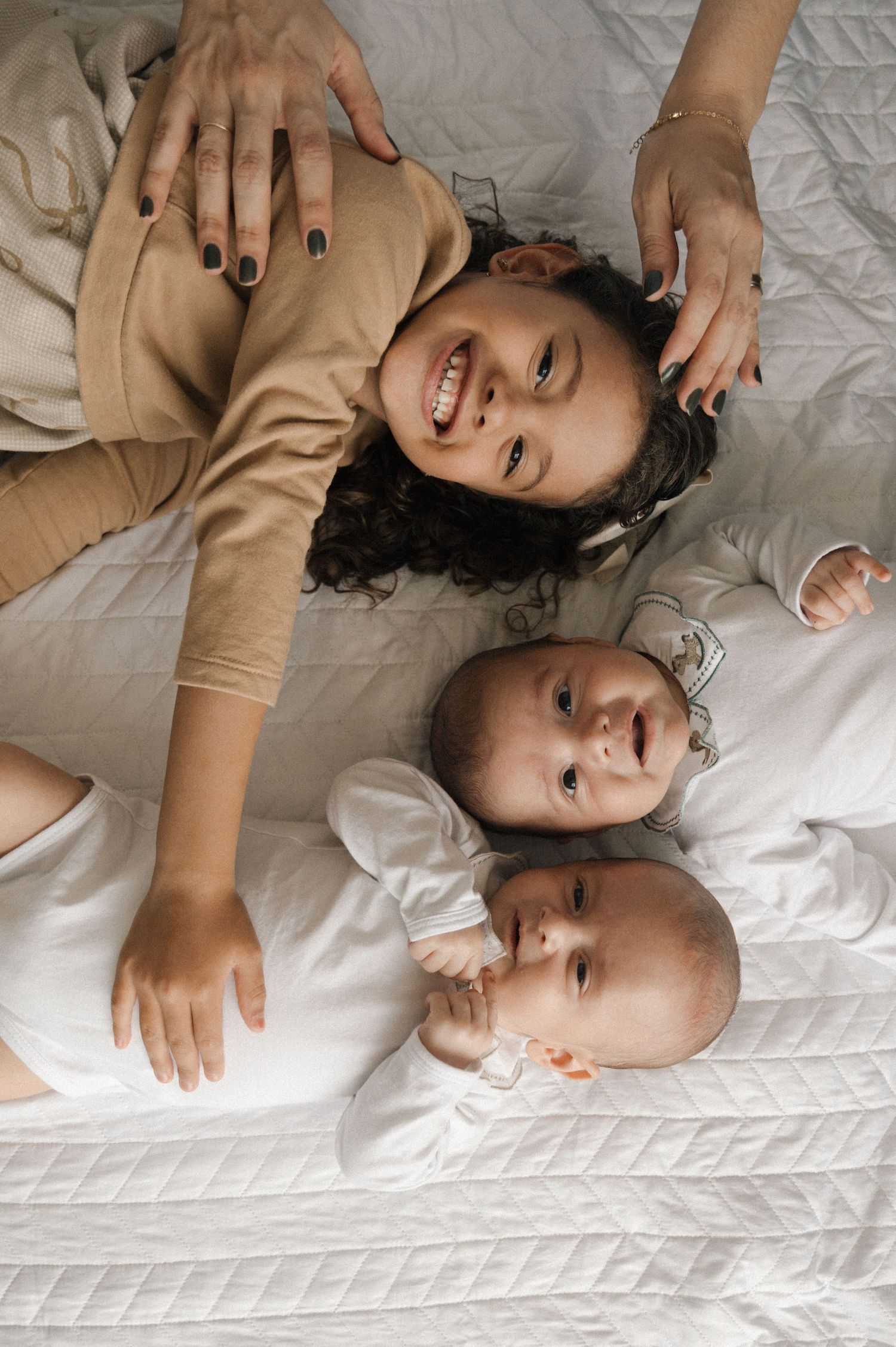 A series of tender moments captured on white bedding showing affectionate interaction between parent and baby.