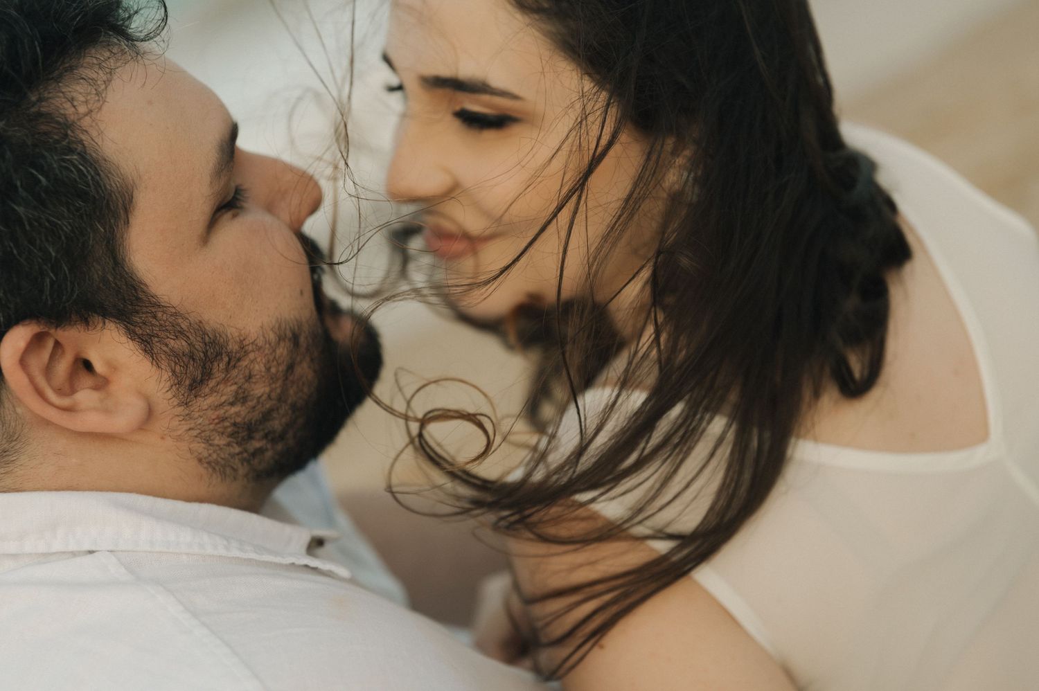 An intimate close-up of a couple in white clothing sharing a tender moment.