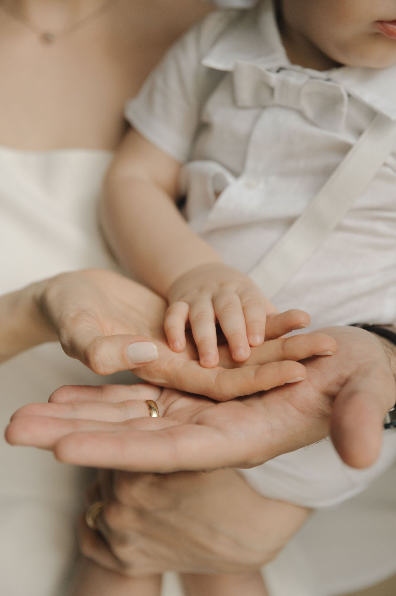 Close-up sequence of gentle hands touching and holding each other against a soft white background.