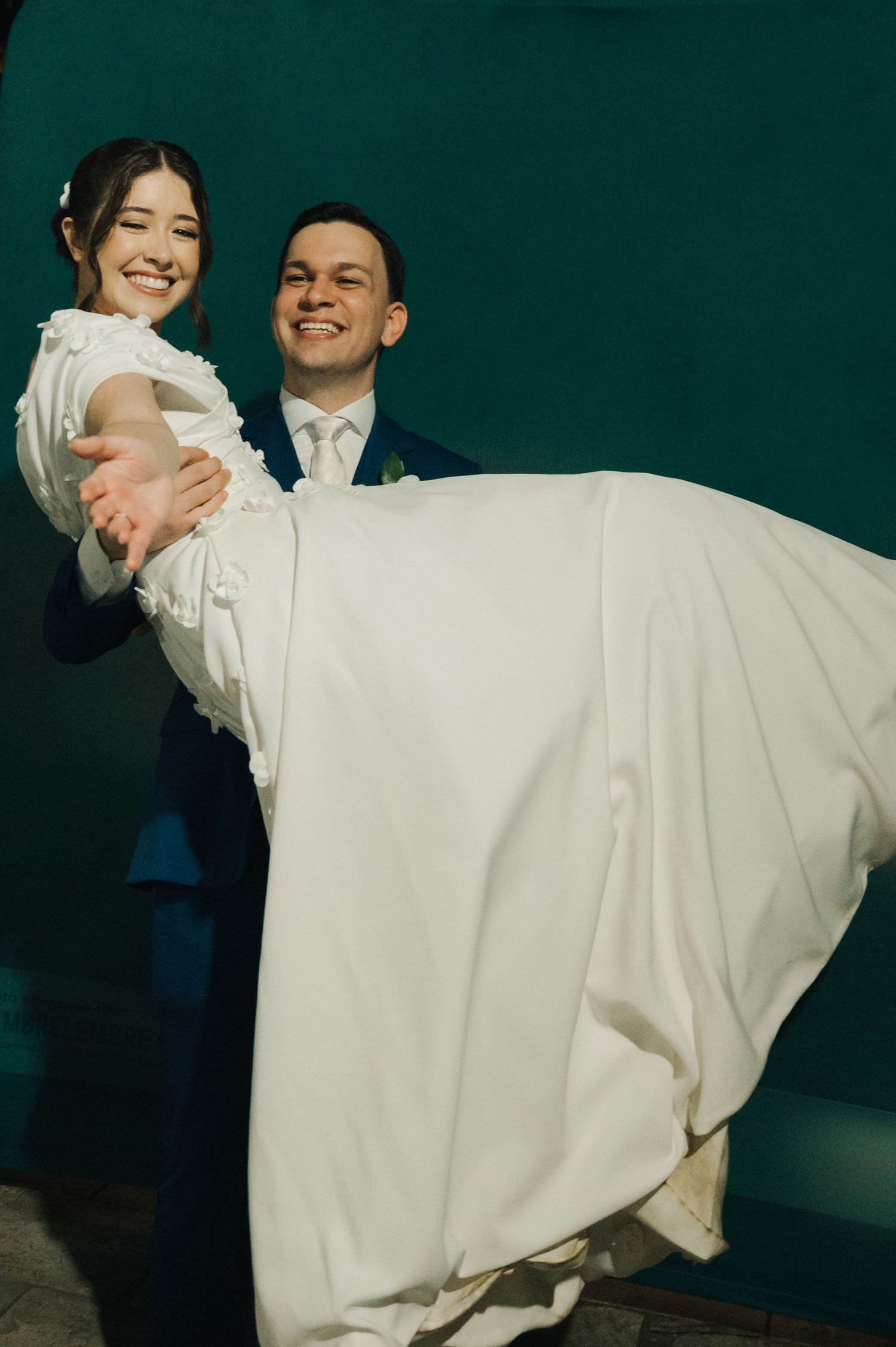 A traditional wedding carry pose against a dark green background.