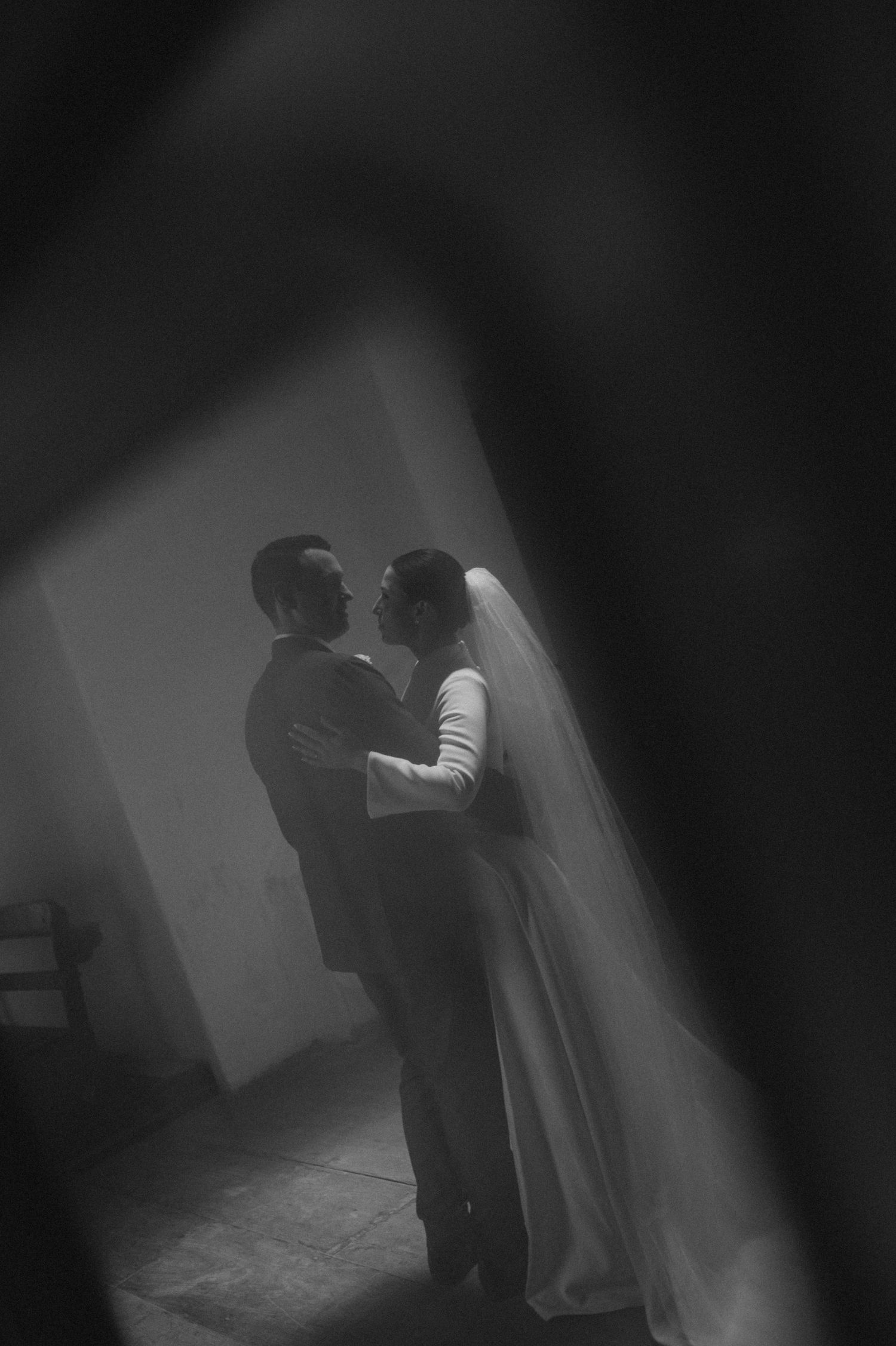 Romantic black and white silhouette of bride and groom embracing tenderly before their wedding ceremony.
