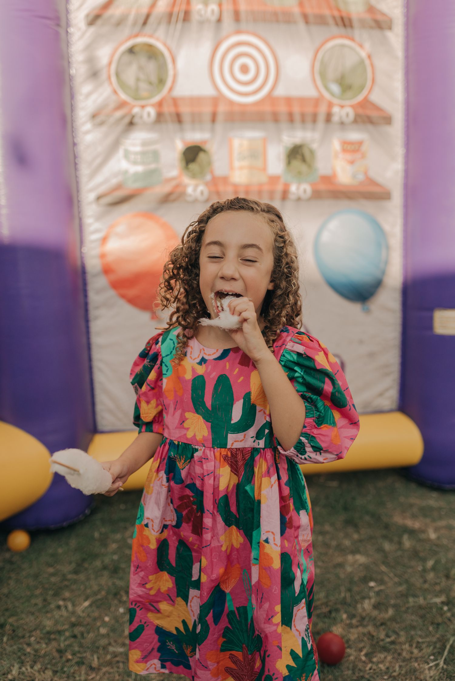 Festive party scene with colorful floral dress against balloon backdrop.