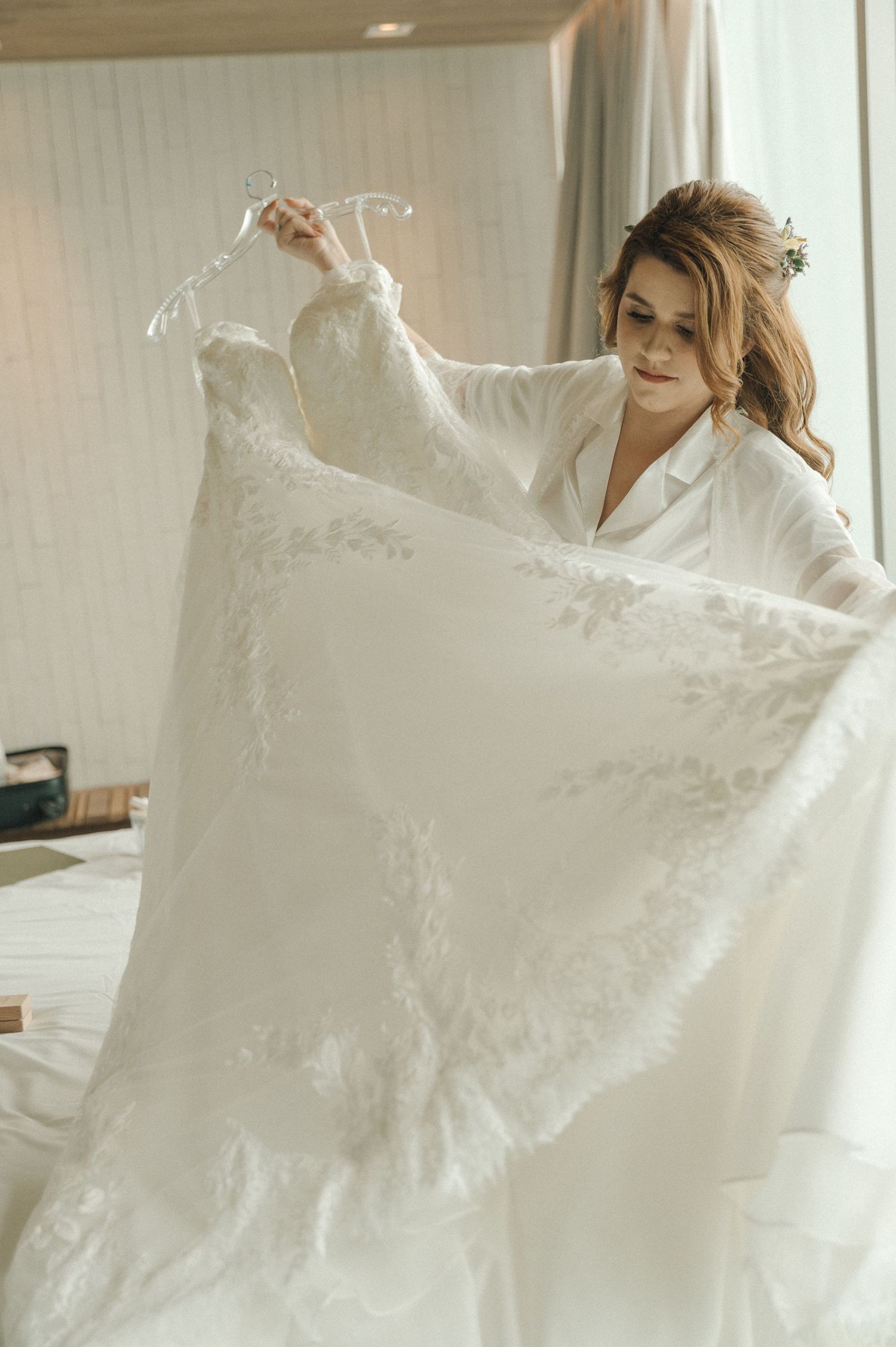 A series of photos showing a white lace wedding dress being held up and displayed in a bright interior setting.