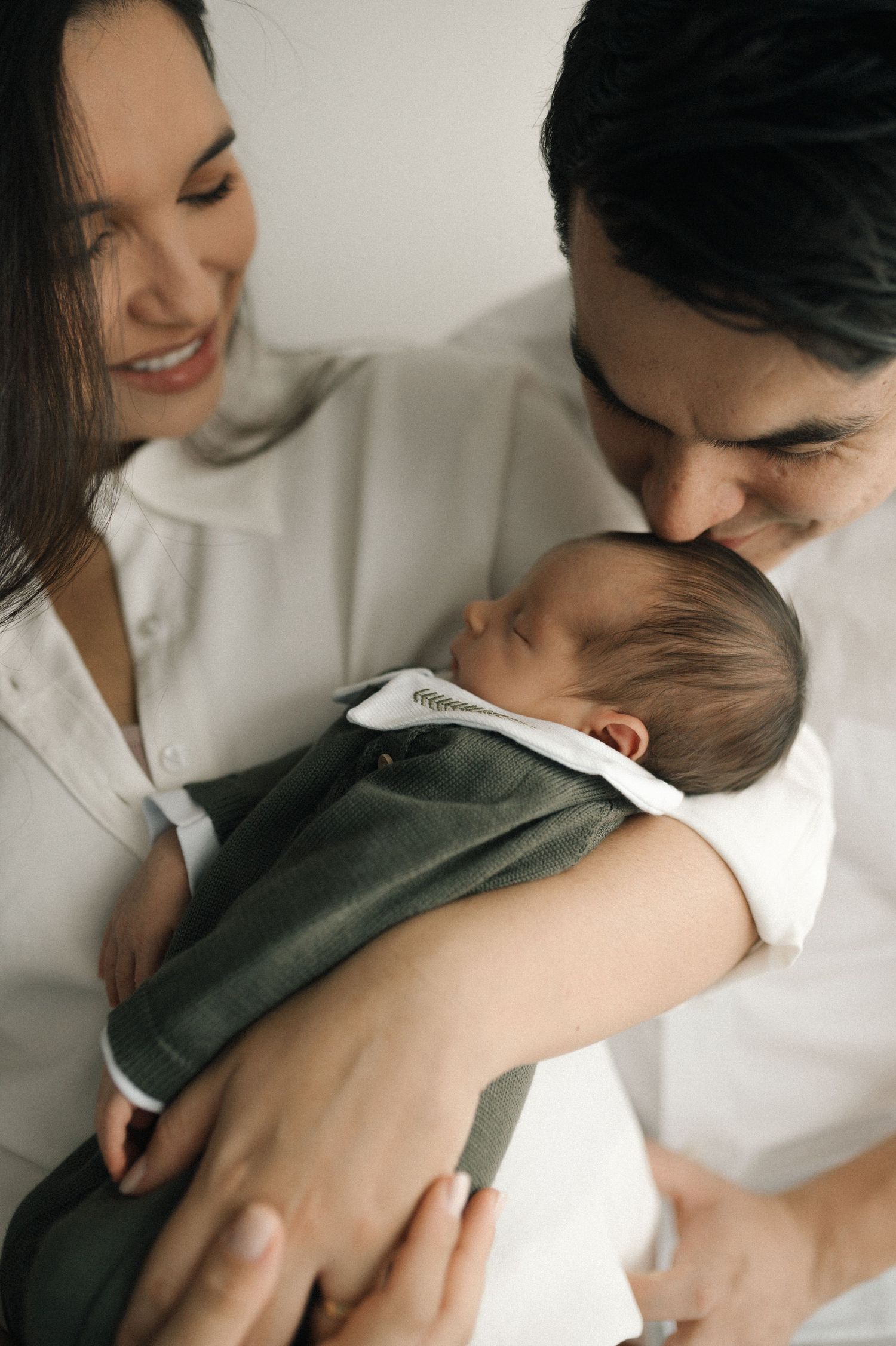 A tender moment showing affection between two people in white and olive green clothing.