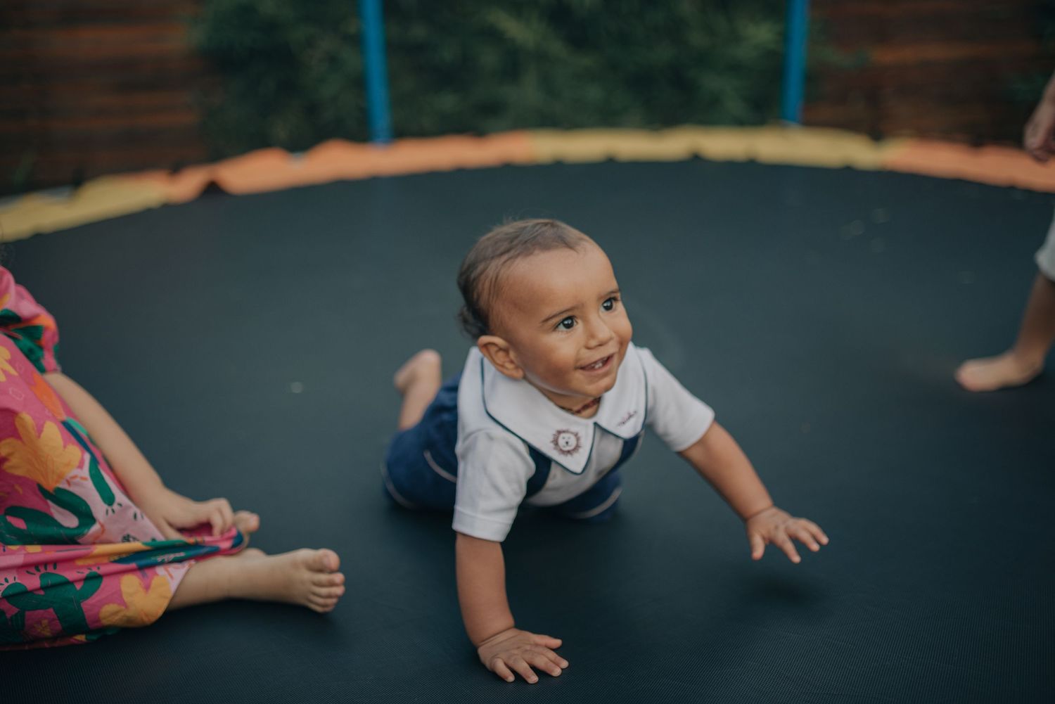 Young toddler crawling on a black trampoline during outdoor playtime.
