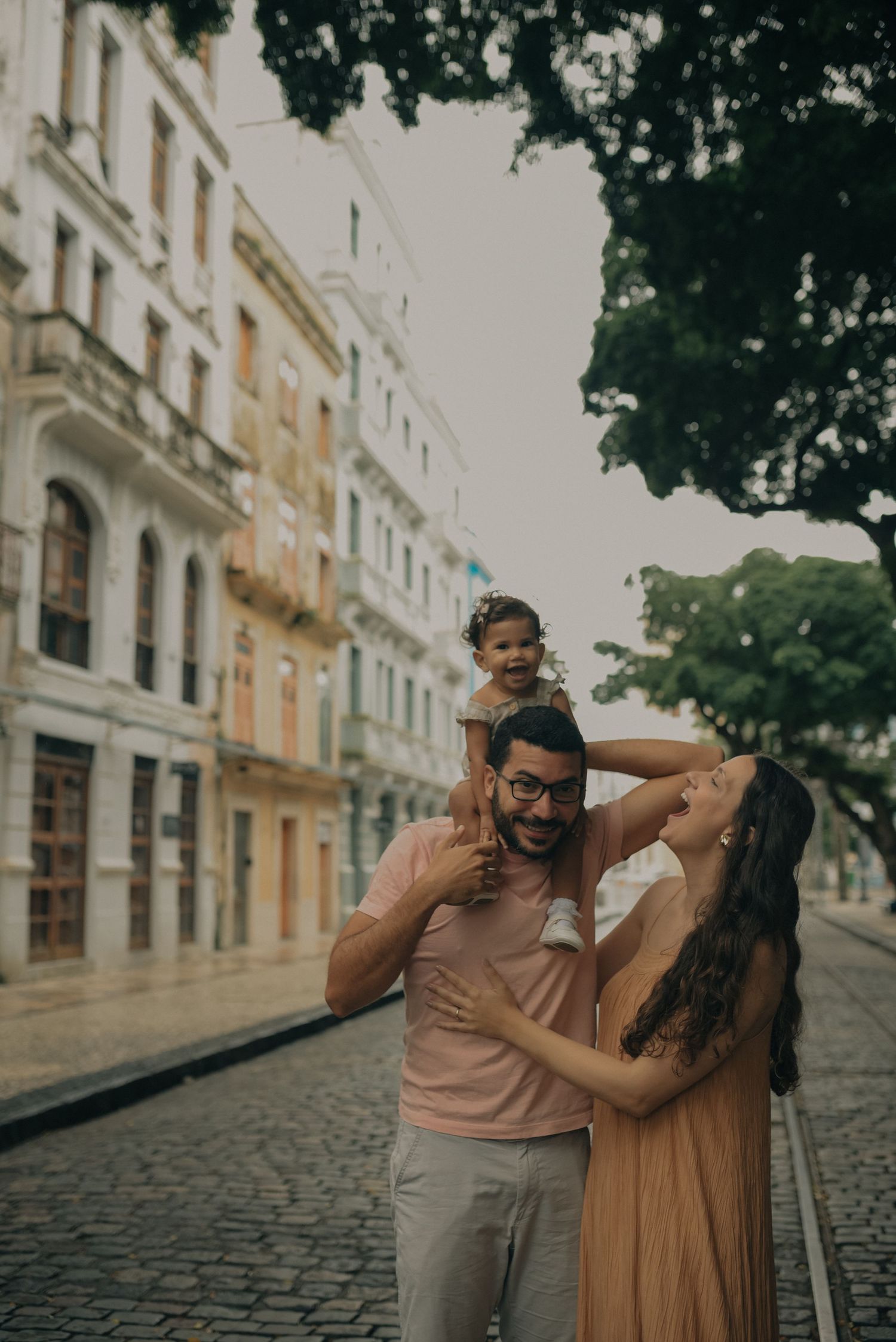 Joyful family moment on a historic cobblestone street with colonial architecture.