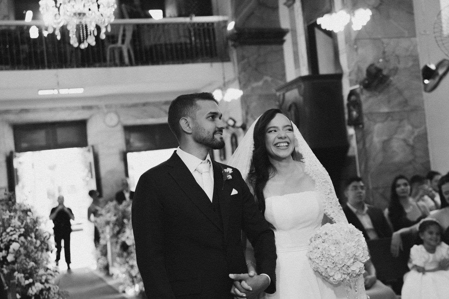 Bride and groom smiling at wedding ceremony in elegant venue, black and white photo.
