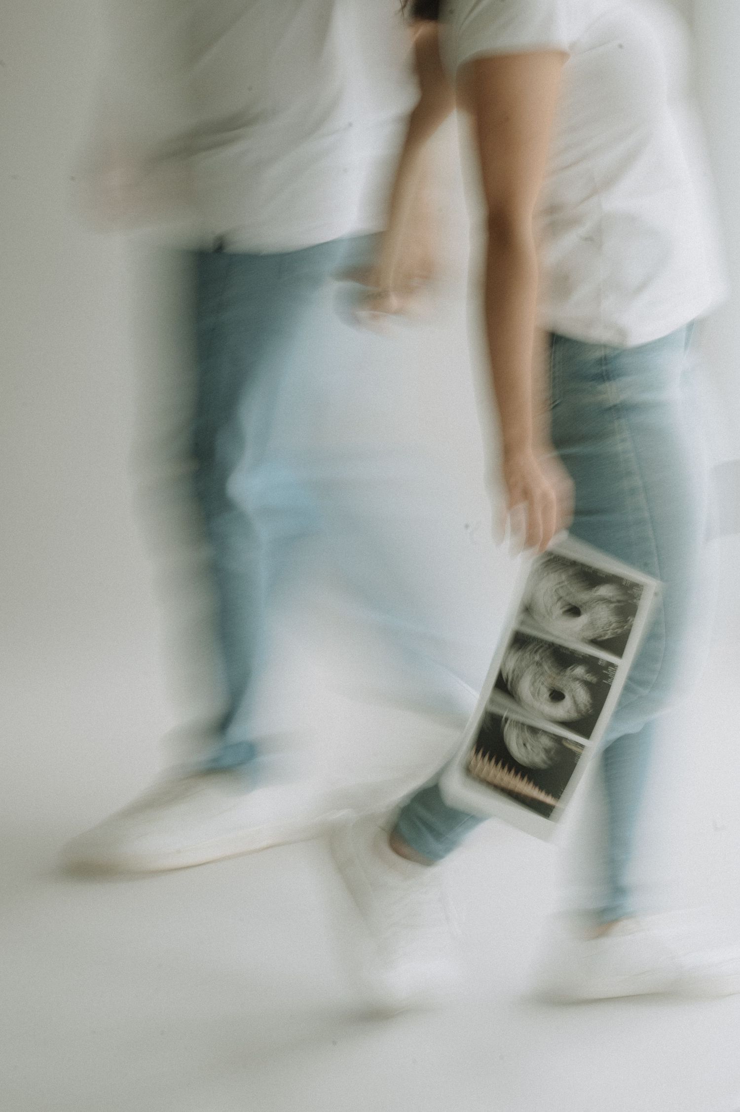 Motion blurred sequence of someone holding a vintage photograph or polaroid against light colored background.