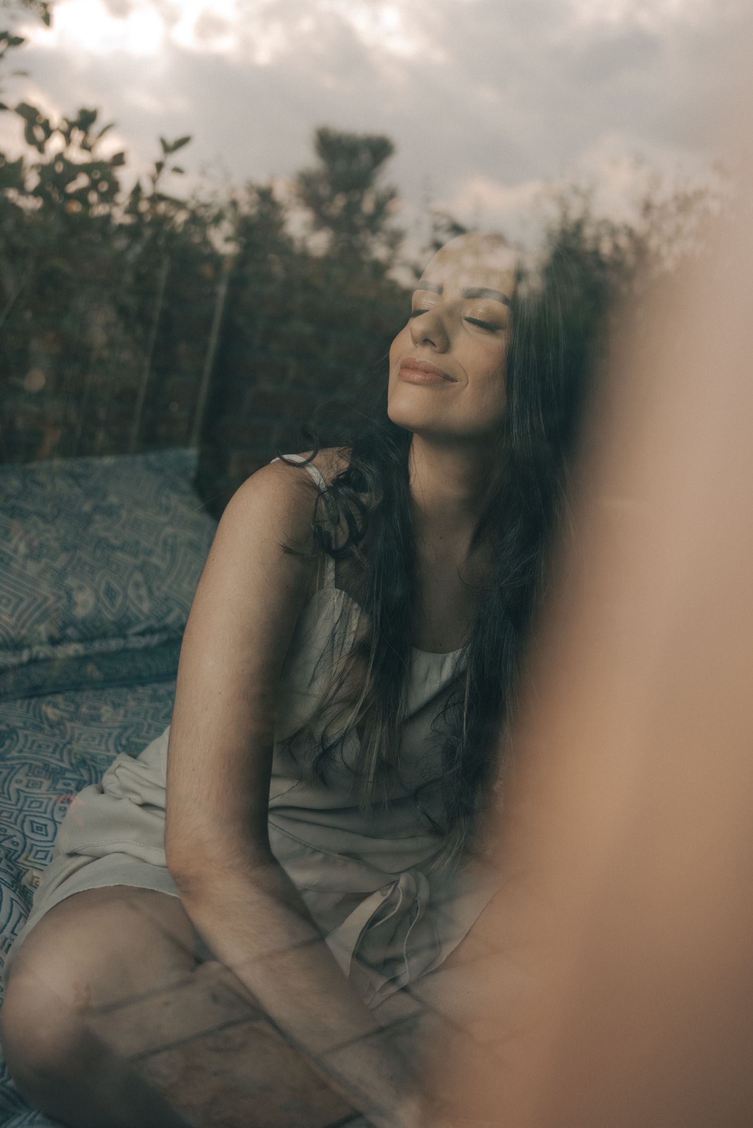 Dreamy outdoor portrait of someone relaxing with eyes closed in natural setting.