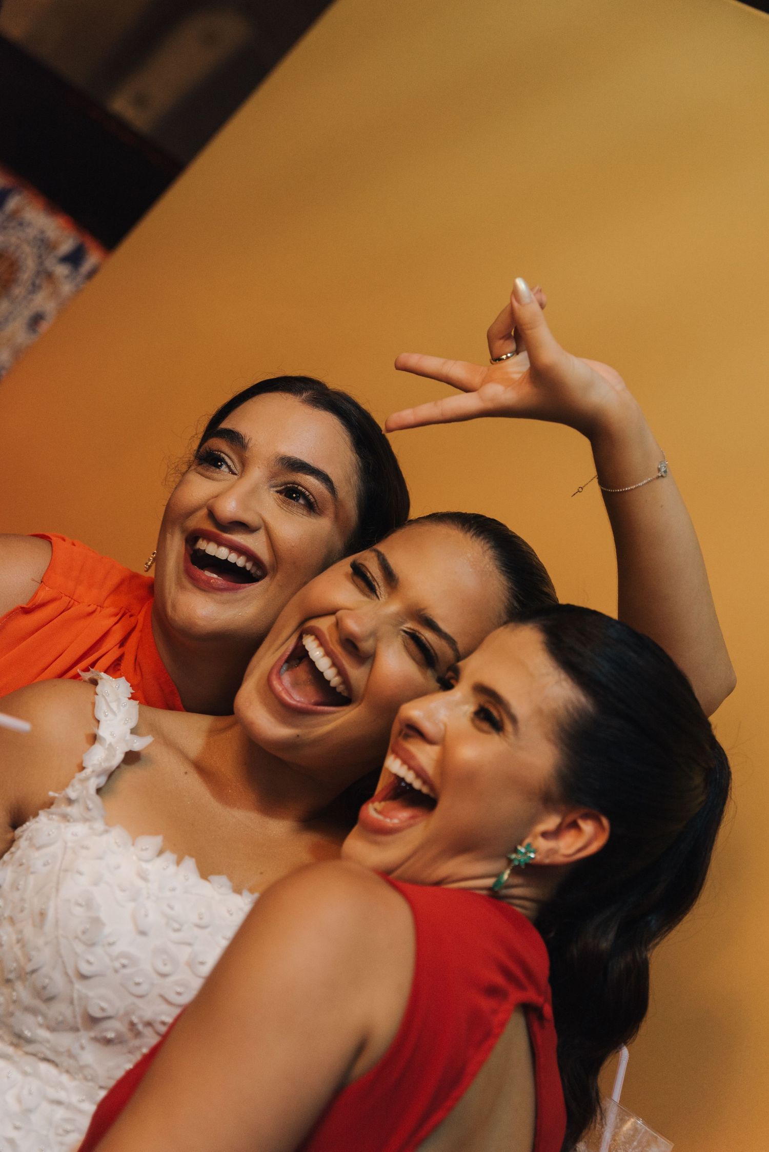 Three women laughing and posing together at a wedding celebration.