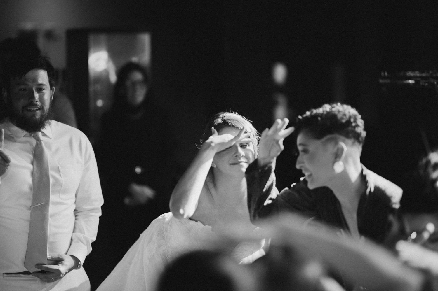 Monochrome series of photos showing people interacting at what appears to be a wedding reception in a dim-lit venue.