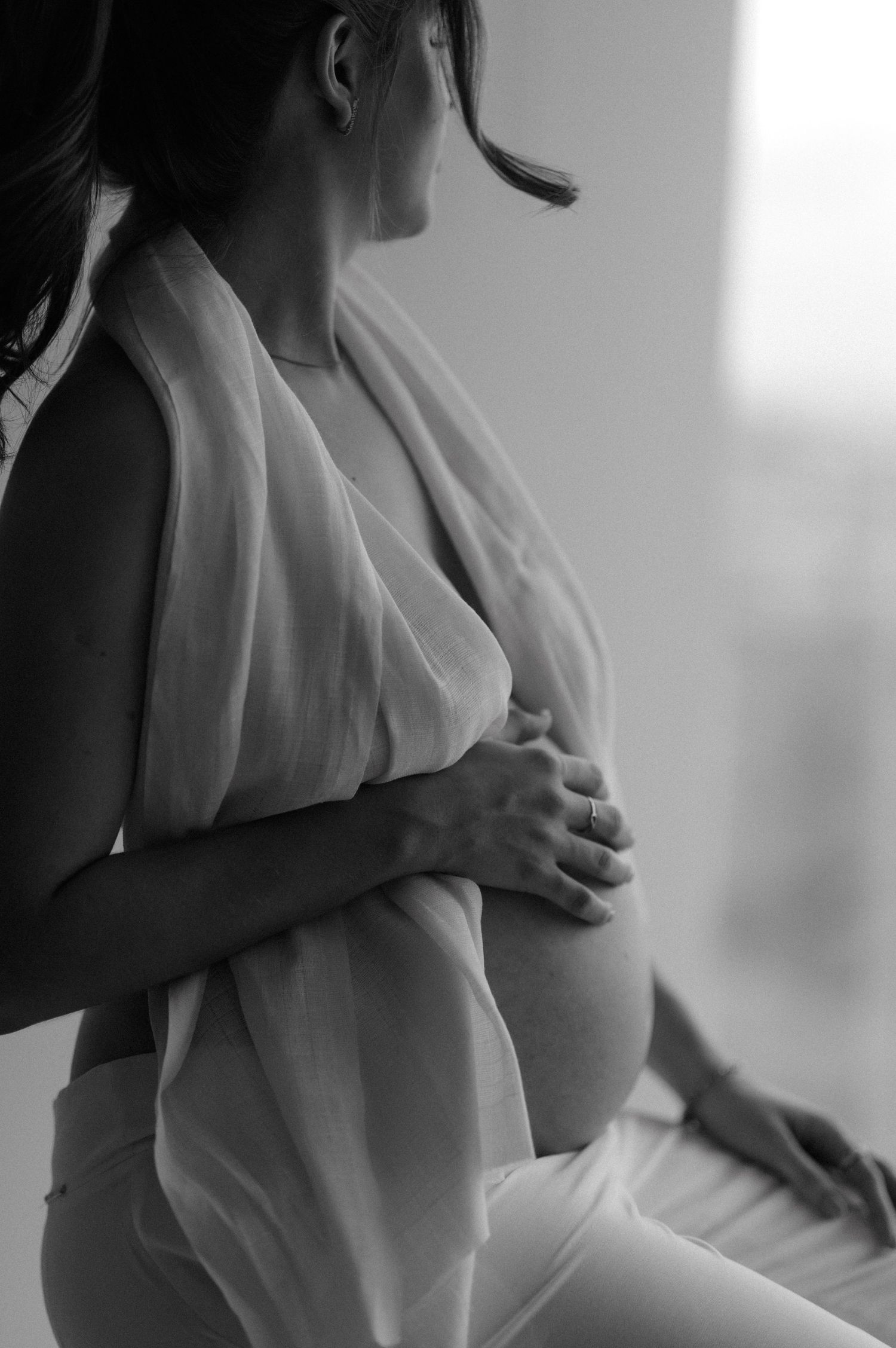 Black and white maternity photo showing gentle hands cradling a baby bump.