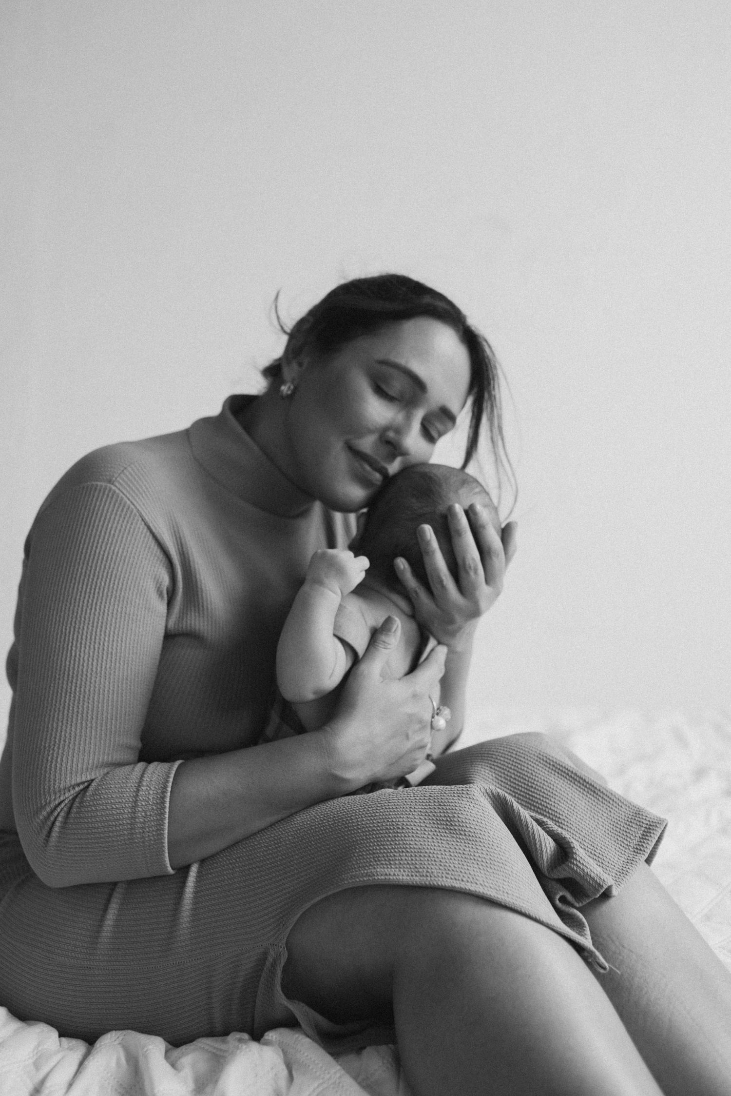 Peaceful black and white image of parent cradling newborn in cozy knit clothing.