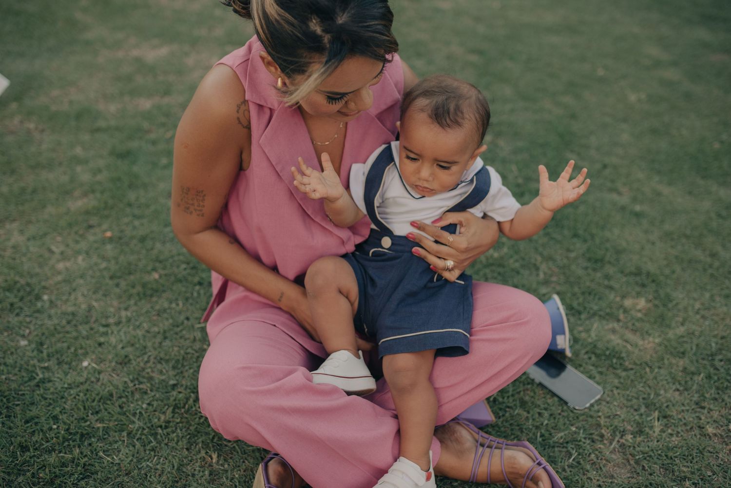 Casual outdoor moment on grass with pink jumpsuit attire.