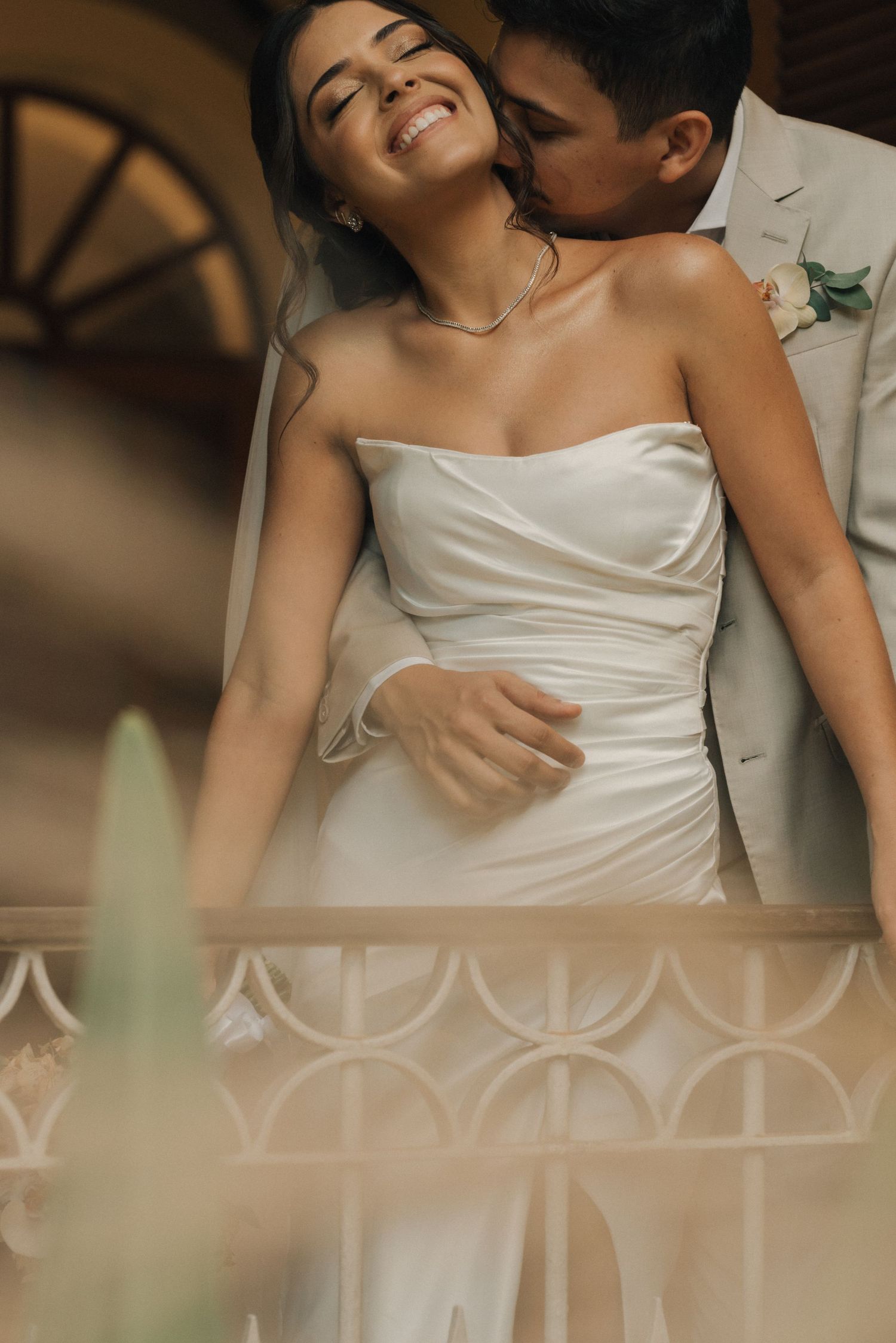 An intimate moment between newlyweds sharing affection in front of decorative architecture.