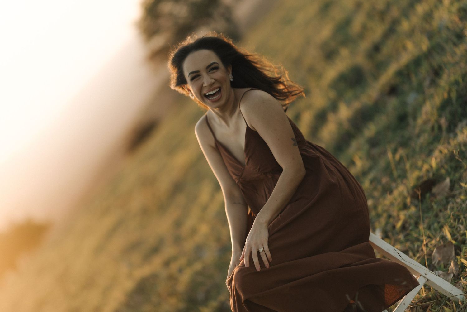 Sunset portrait on a grassy hillside with warm golden lighting.