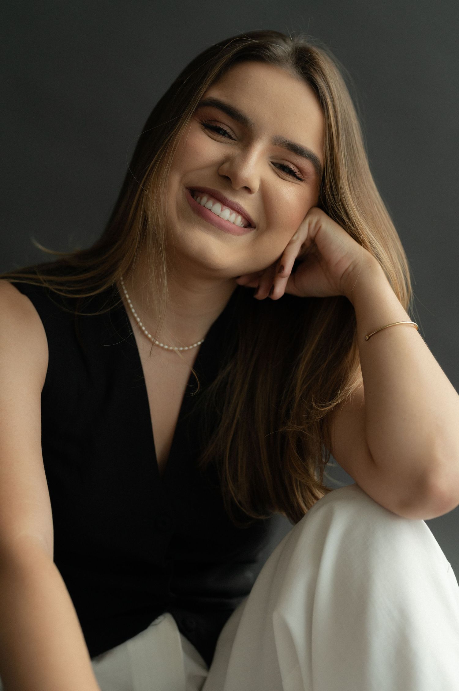 Elegant studio portrait with black top and delicate pearl necklace.