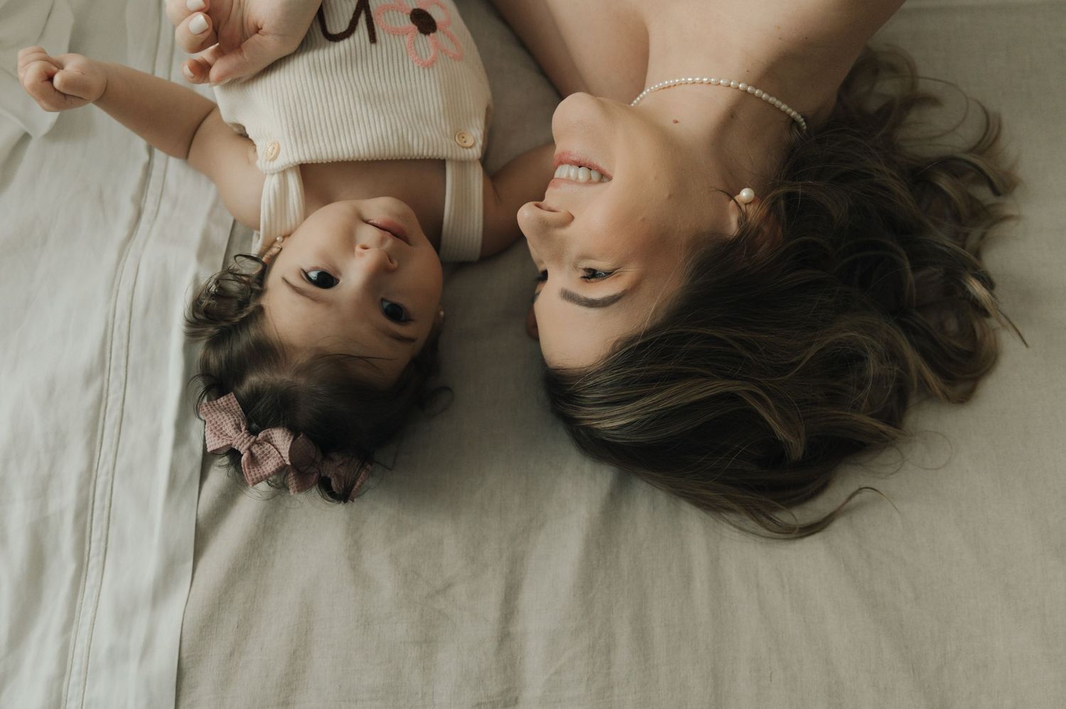 A series of artistic portrait photos showing a person lying on white sheets with hair spread out in different poses.