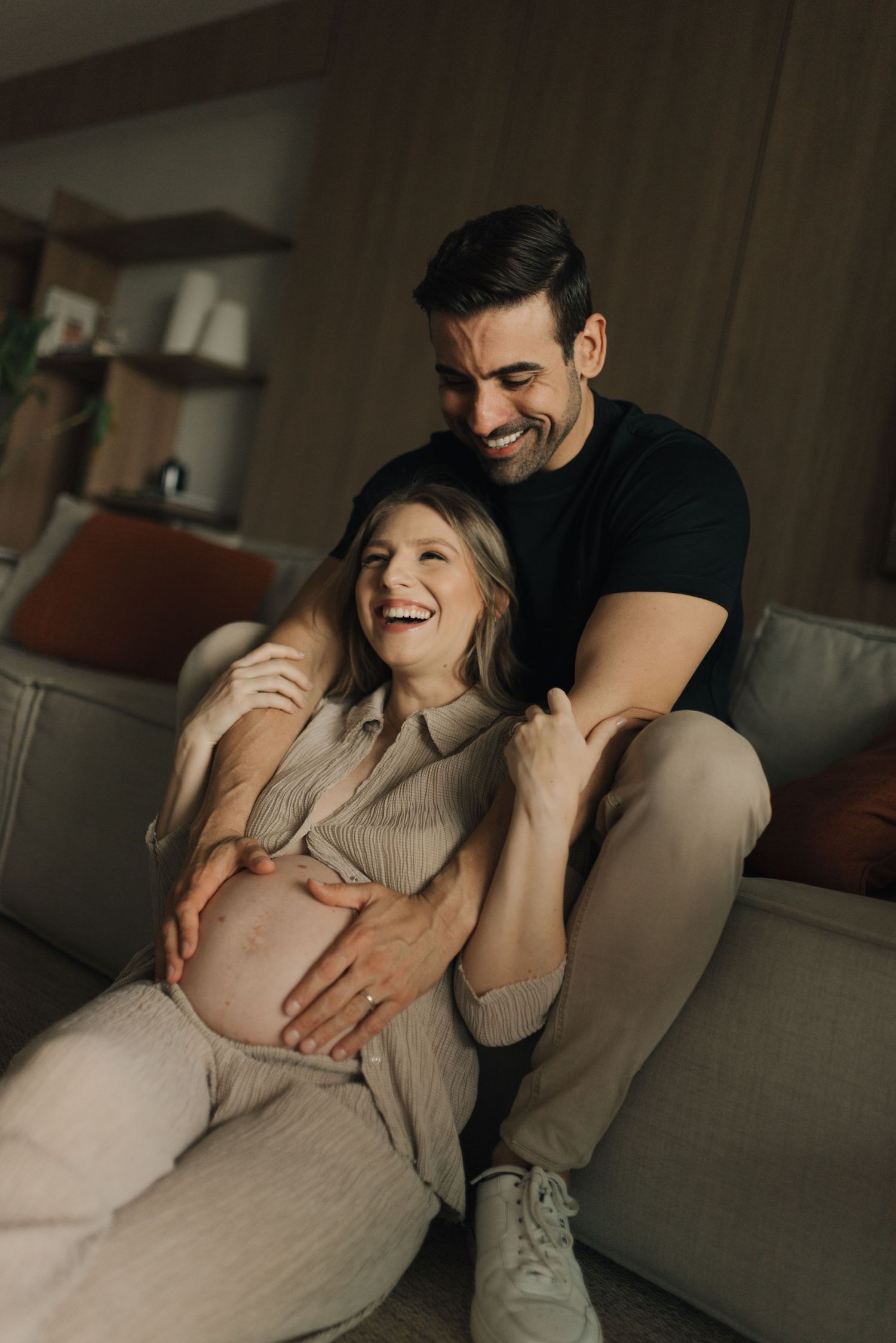 Cozy maternity moment shared on a living room couch.