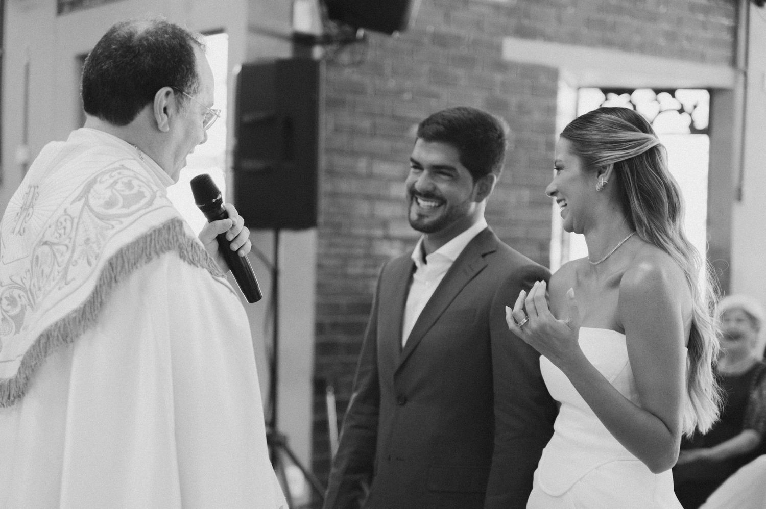 Wedding ceremony moment with couple and officiant at indoor brick venue.