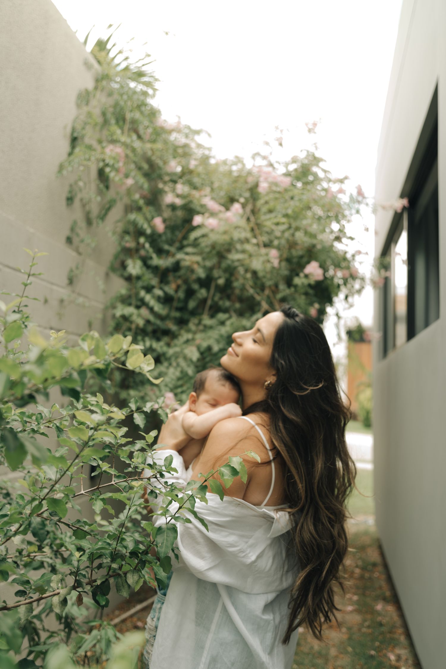 A peaceful garden scene showing mother-child bonding amongst flowering vines and greenery.