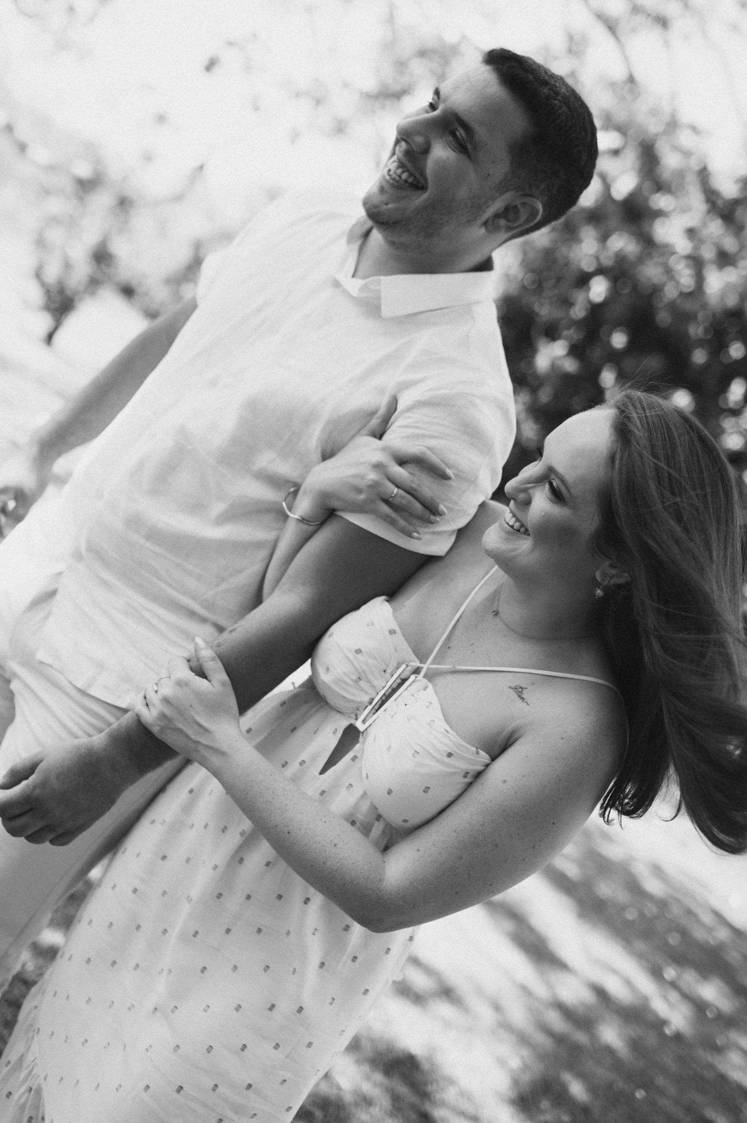 A joyful couple laughing together in black and white photography.
