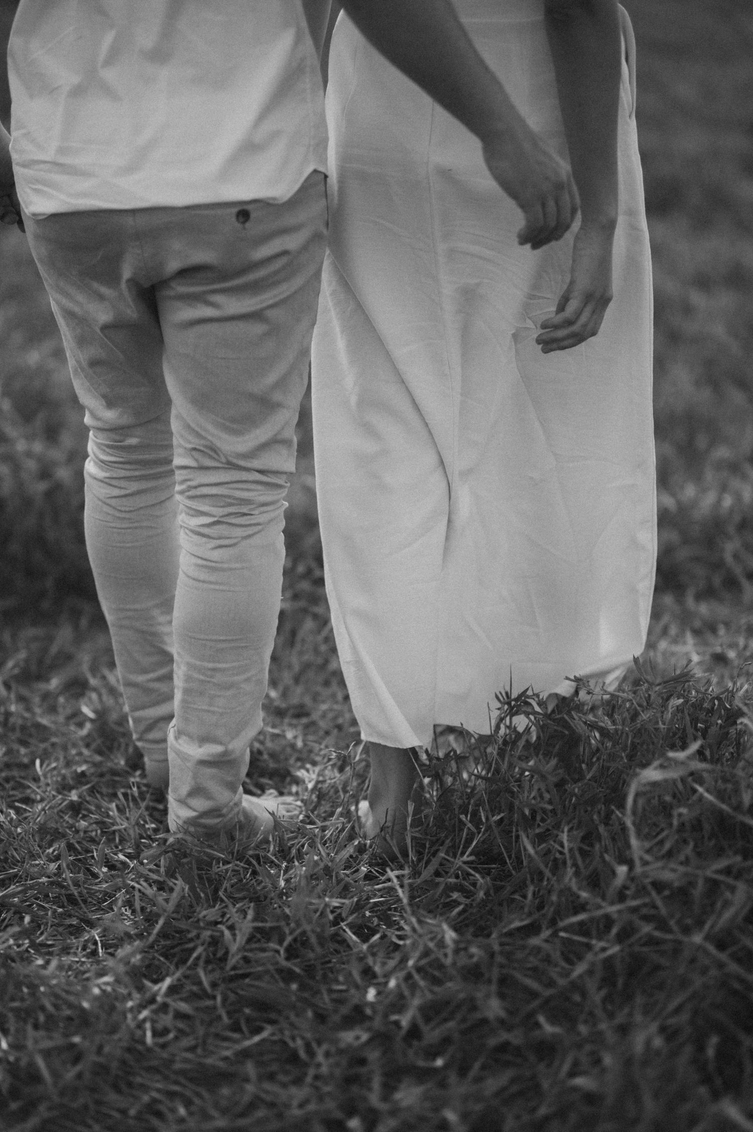 Close-up of two people standing together in white clothing on grass.