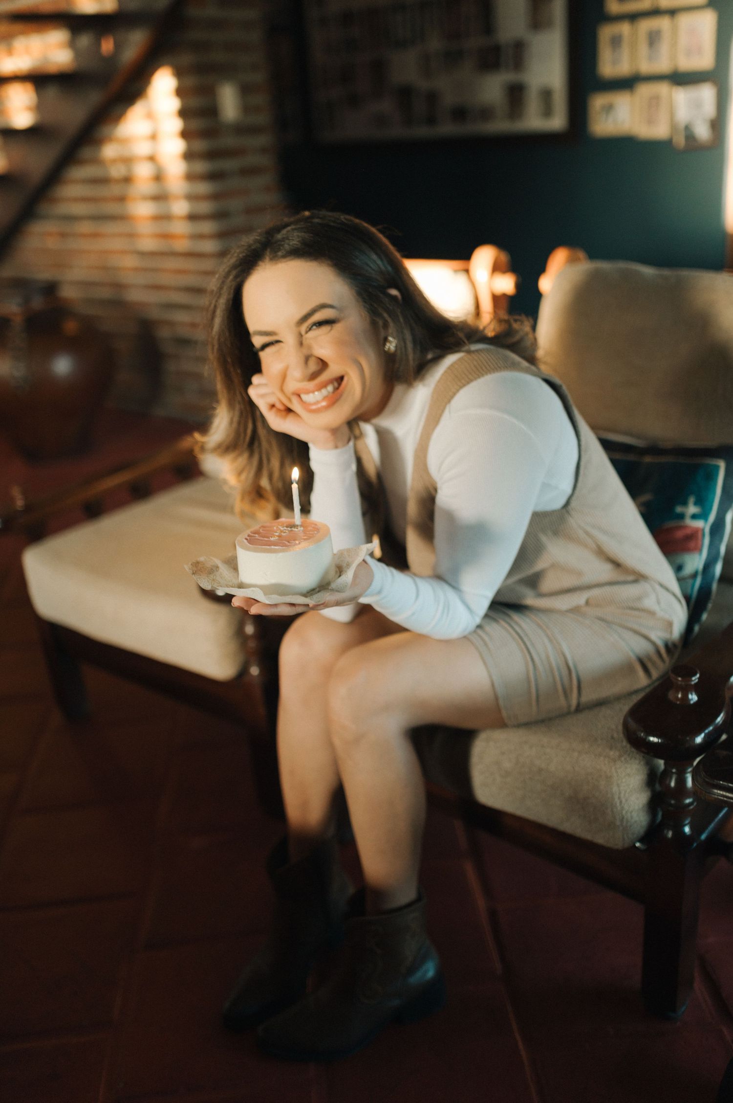 Cozy indoor portrait with someone holding a small birthday cake with candle.