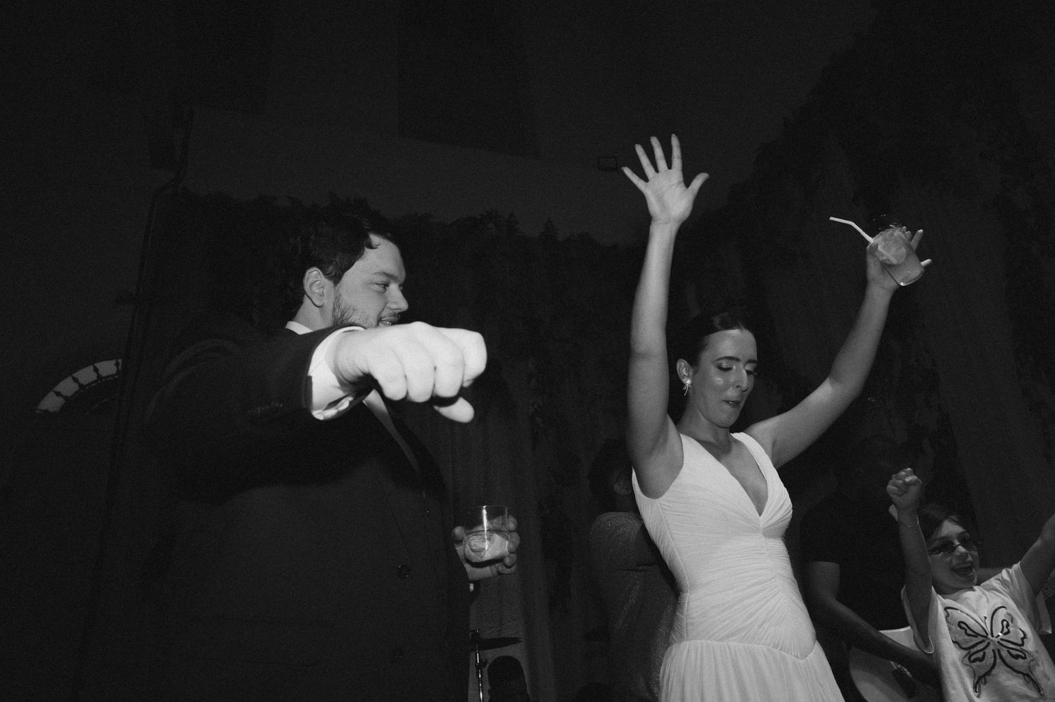 Silhouettes of people dancing with raised arms in a dark nightclub setting with atmospheric lighting effects.