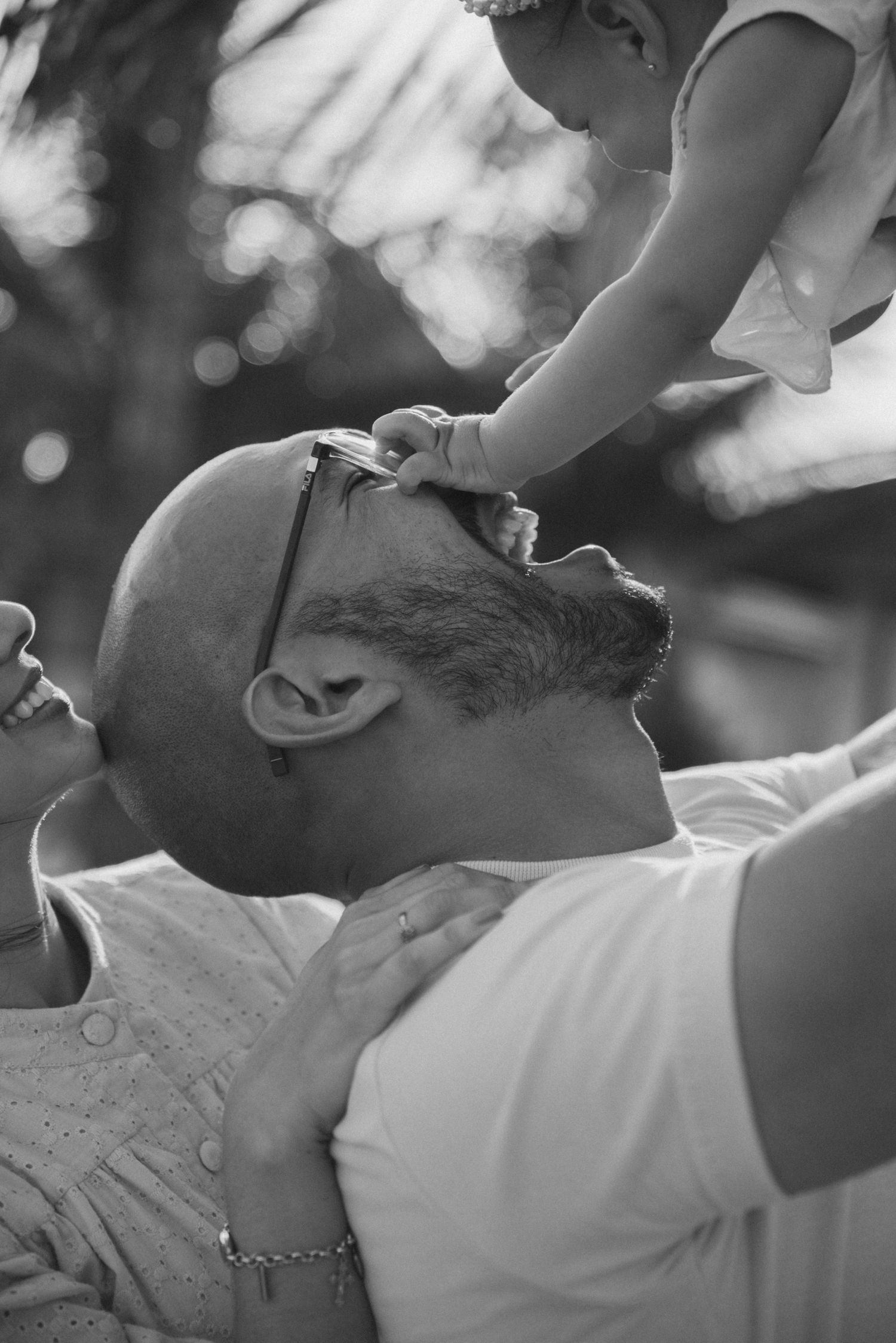 Black and white photo showing joyful interaction between parent and child against bokeh background.
