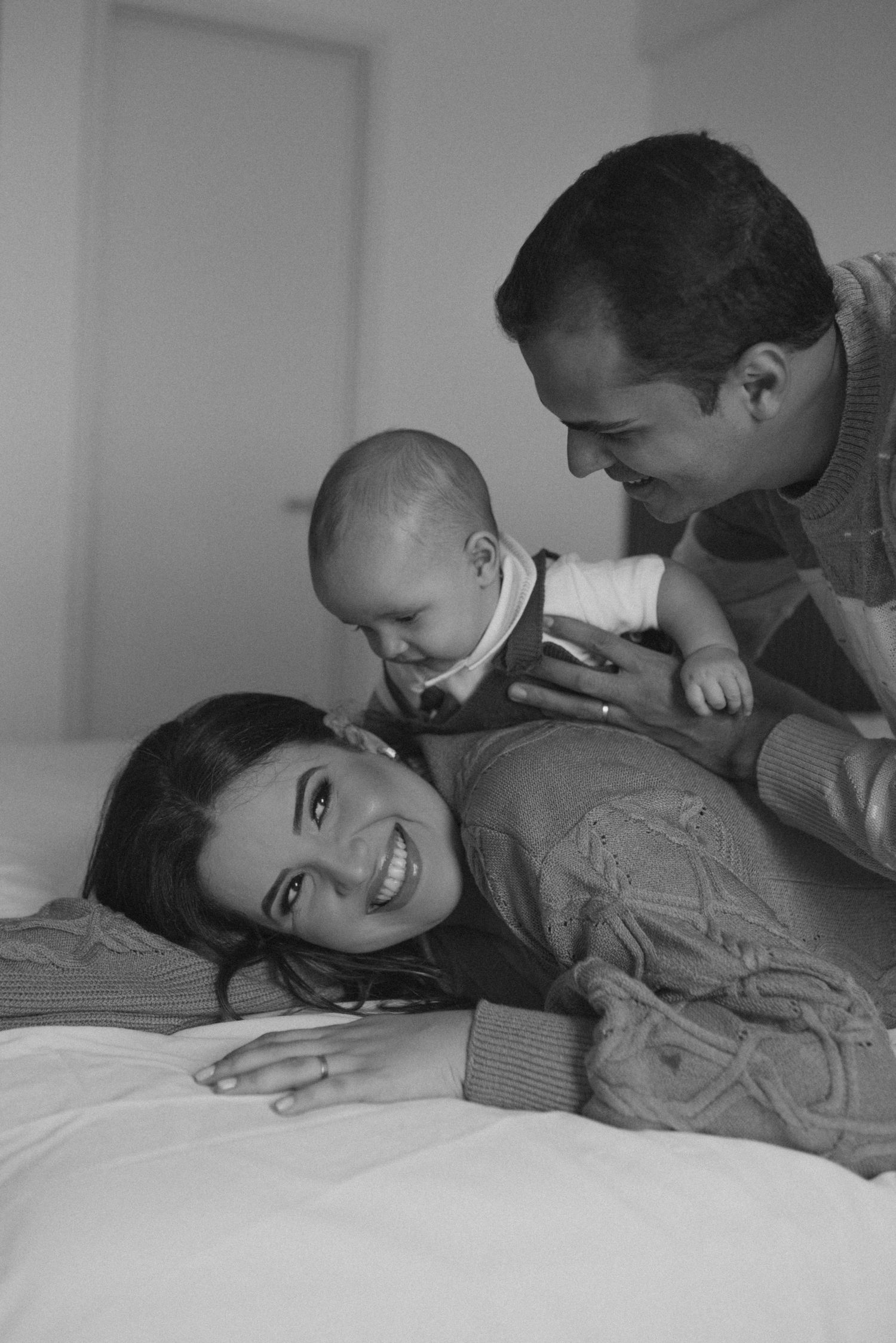 Intimate black and white family portrait showing tender moments together on a bed.