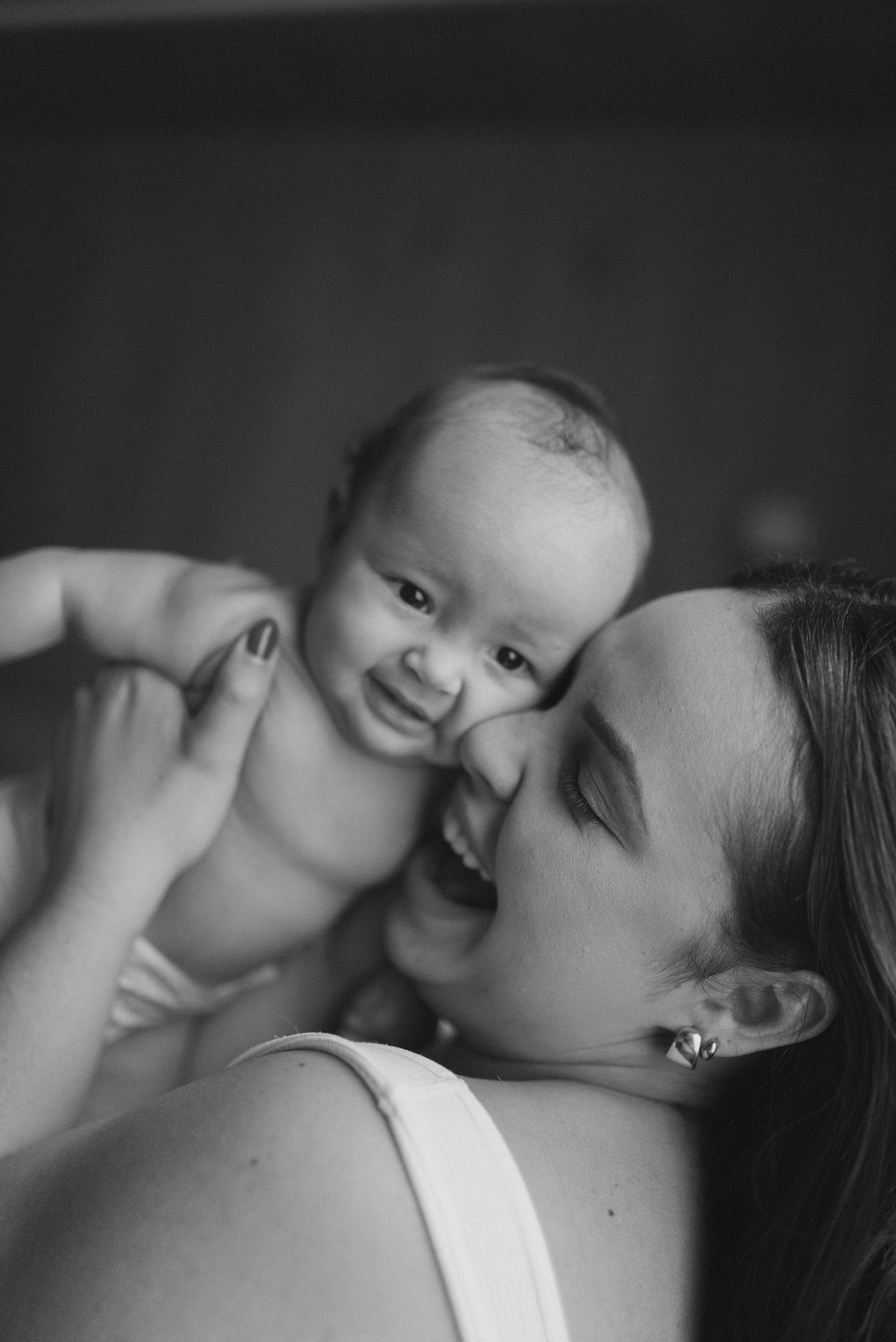 Black and white portrait capturing joyful interaction between parent and baby.