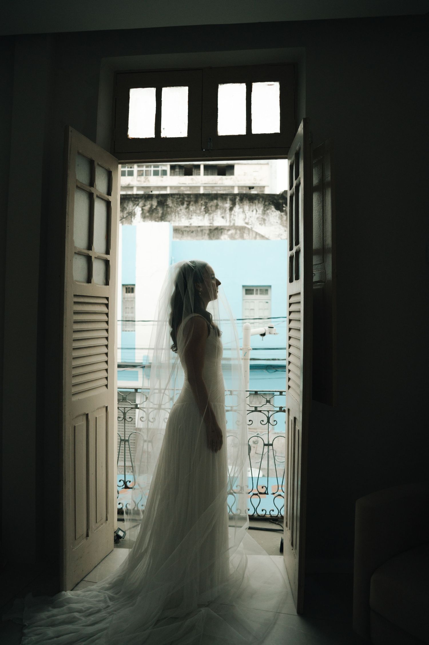 A series of moody silhouettes show a bride in a flowing white dress standing in a doorway against natural light.