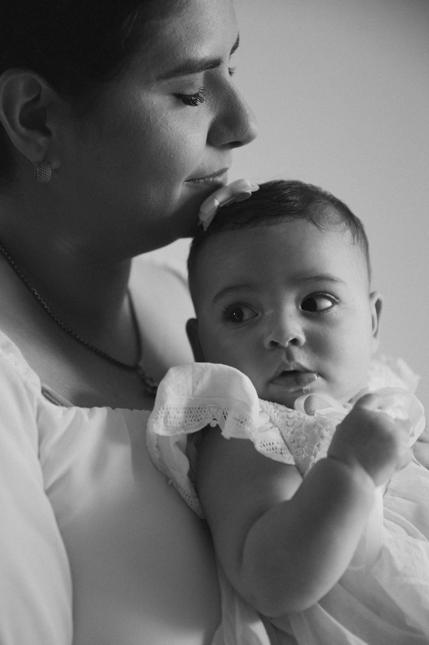 A series of intimate black and white photos showing tender moments between a parent and baby in white clothing.