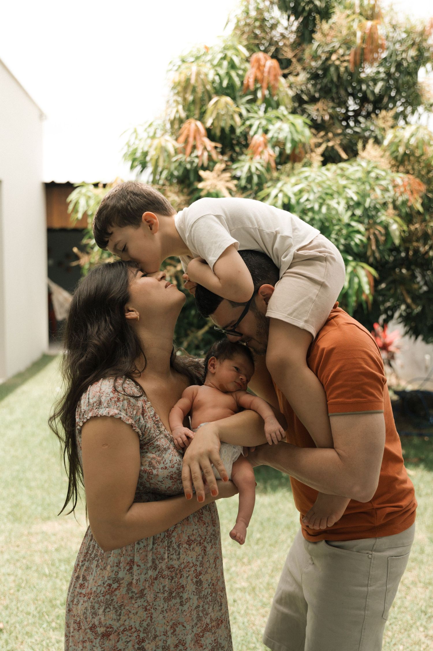 A tender family moment captured in a series of four connected photos showing affectionate embraces outdoors.