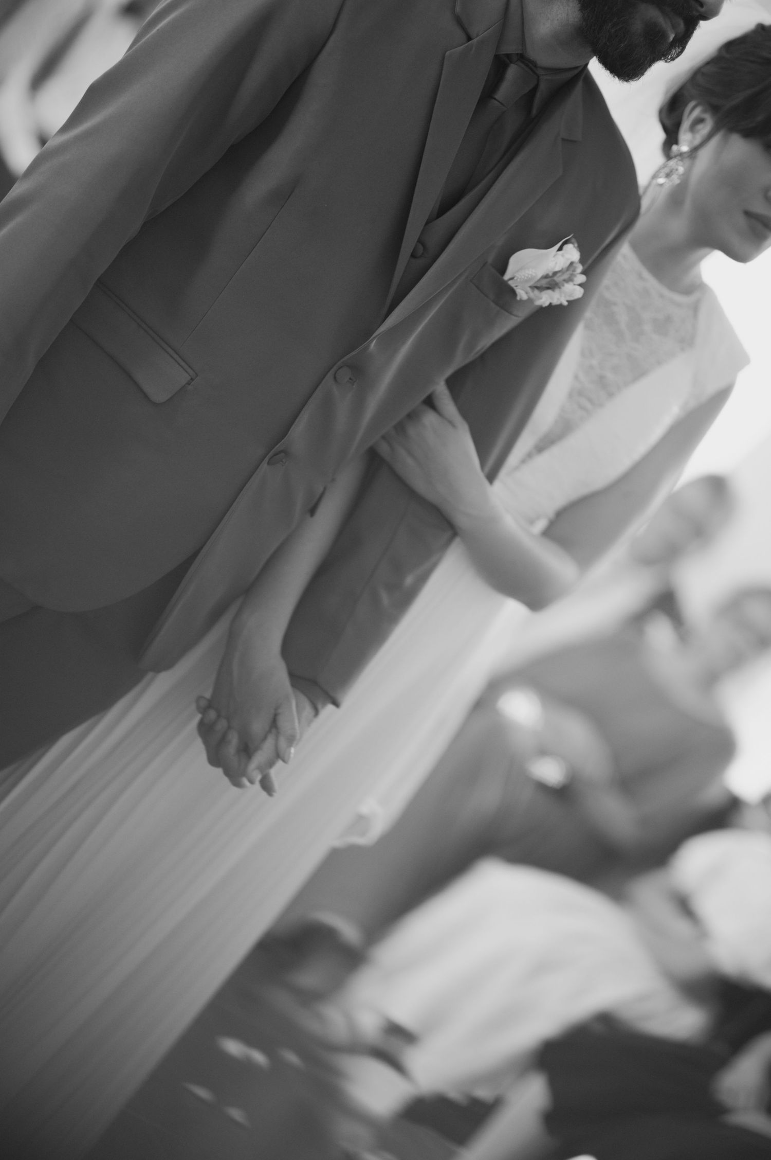 Close-up black and white shot of a groom's formal attire and boutonniere.