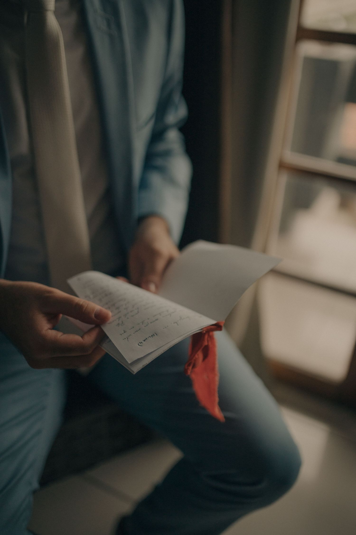 Someone holding and reading a handwritten letter in moody lighting.