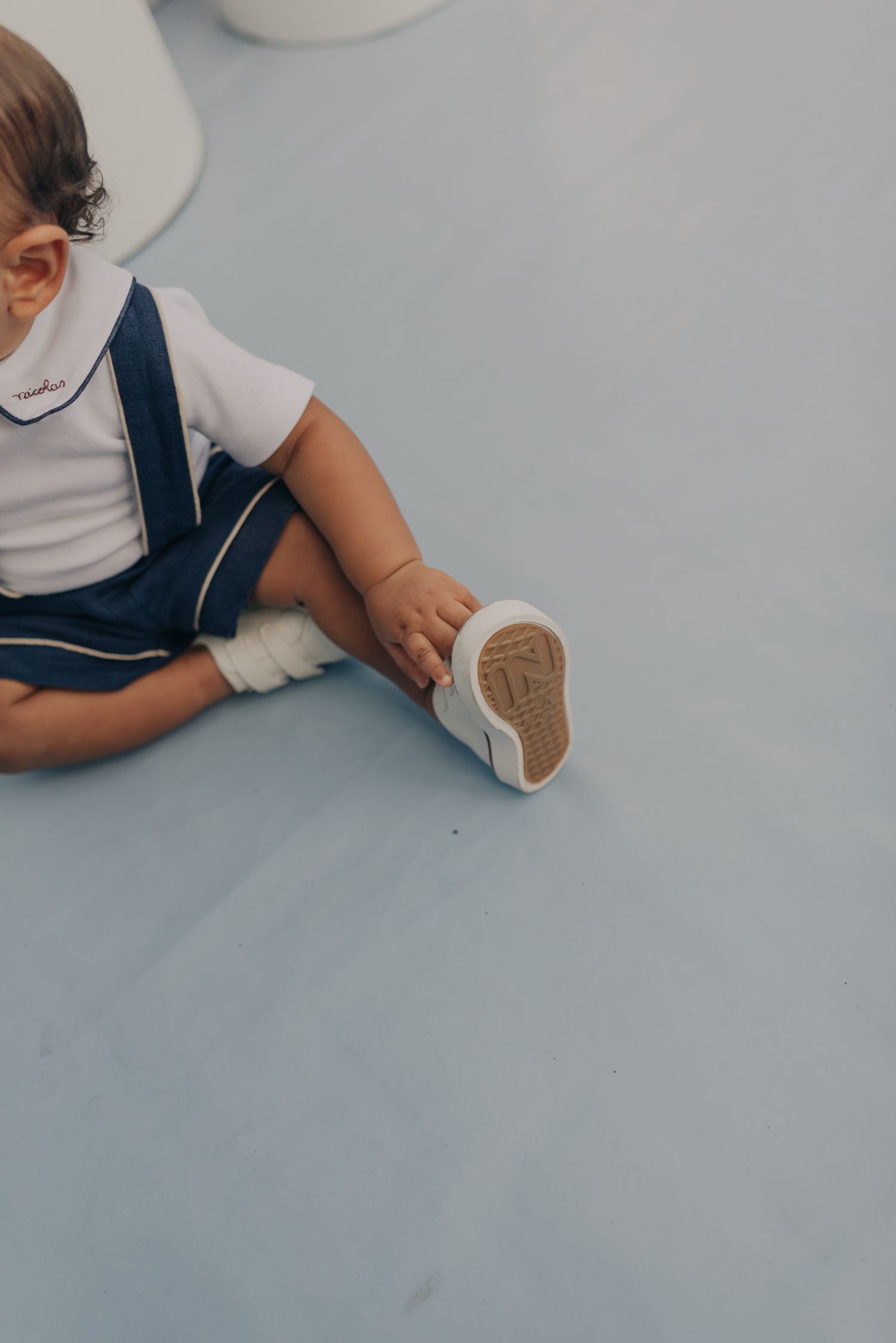 Close-up of small child's feet in white shoes sitting on gray surface.
