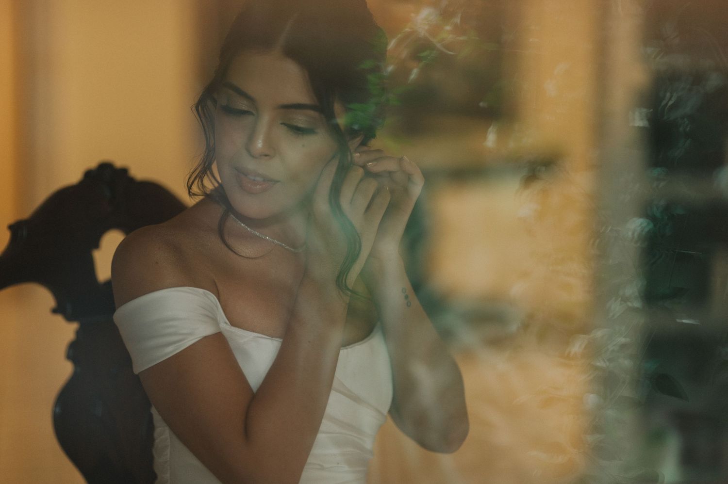 Ethereal portrait of a bride in a white off-shoulder dress with soft golden lighting and smoky atmosphere.